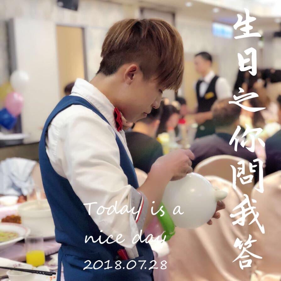 柯男穿藍色背心紅領結在宴會廳低頭折白色氣球，圖上寫生日之你問我答 2018.07.28