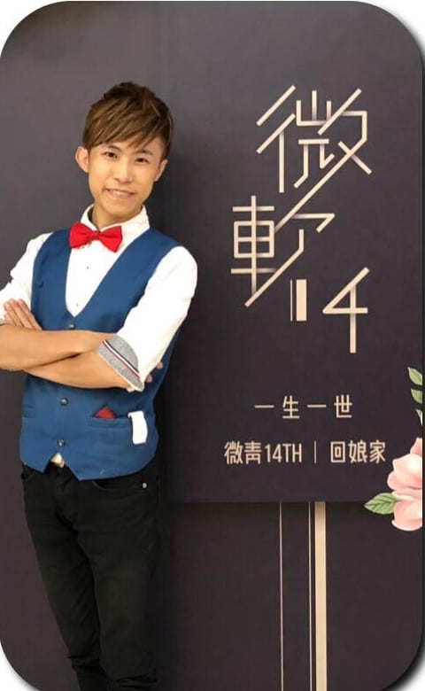 柯男雙手抱胸站在微動 14 一生一世深藍背板前合照