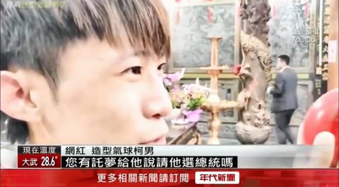 年代新聞播出柯男在廟內手拿紅色筊杯詢問的影片畫面