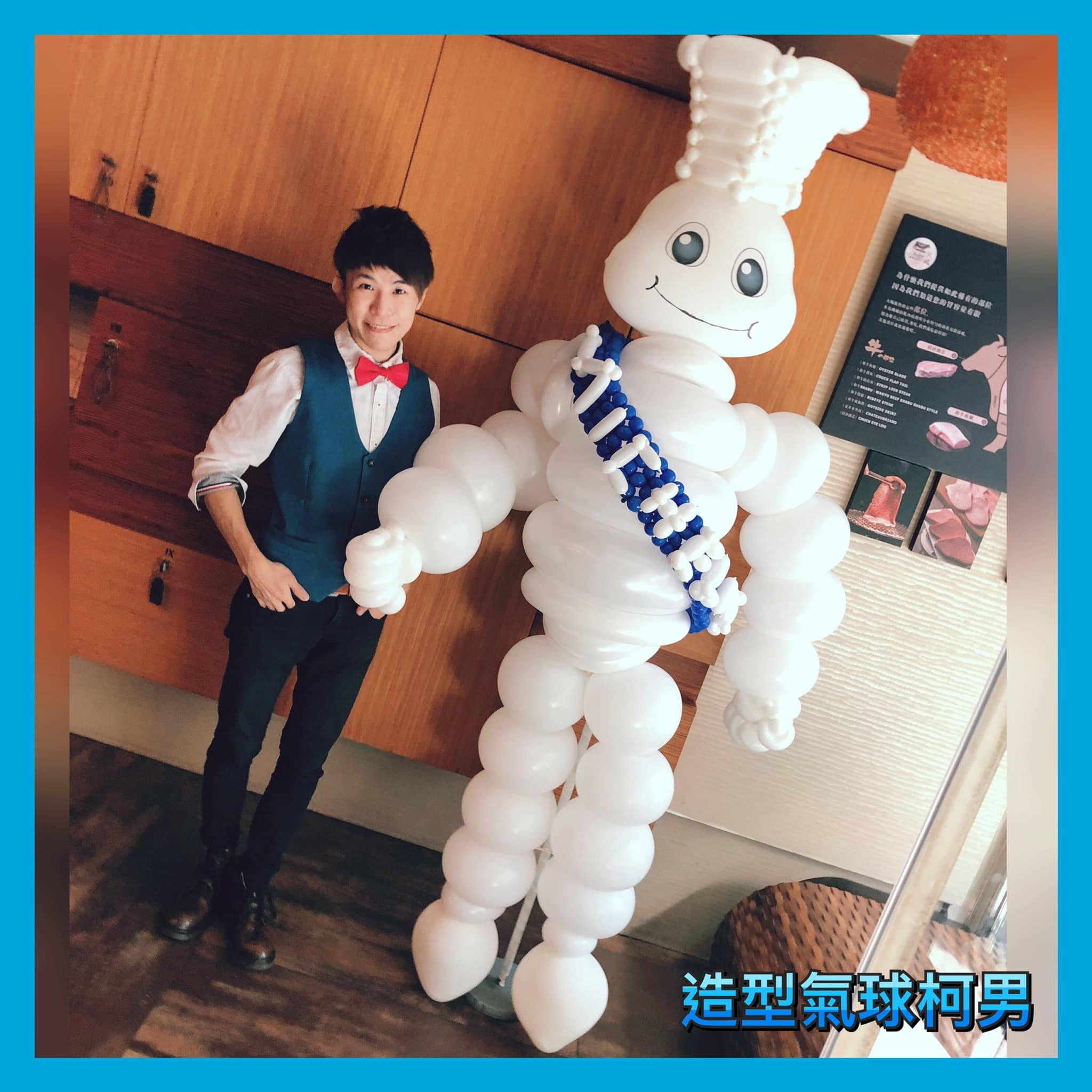 一人高的白色胖胖廚師造型氣球人偶，戴廚師帽、斜背藍色彩帶，擺在餐廳