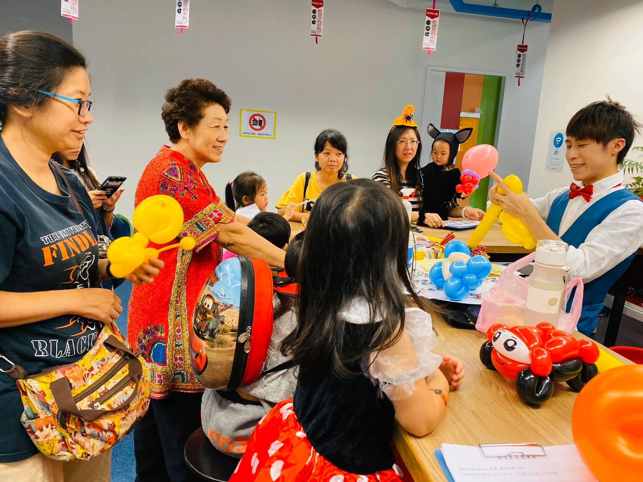 我在桌邊替圍過來的家長和孩子折氣球