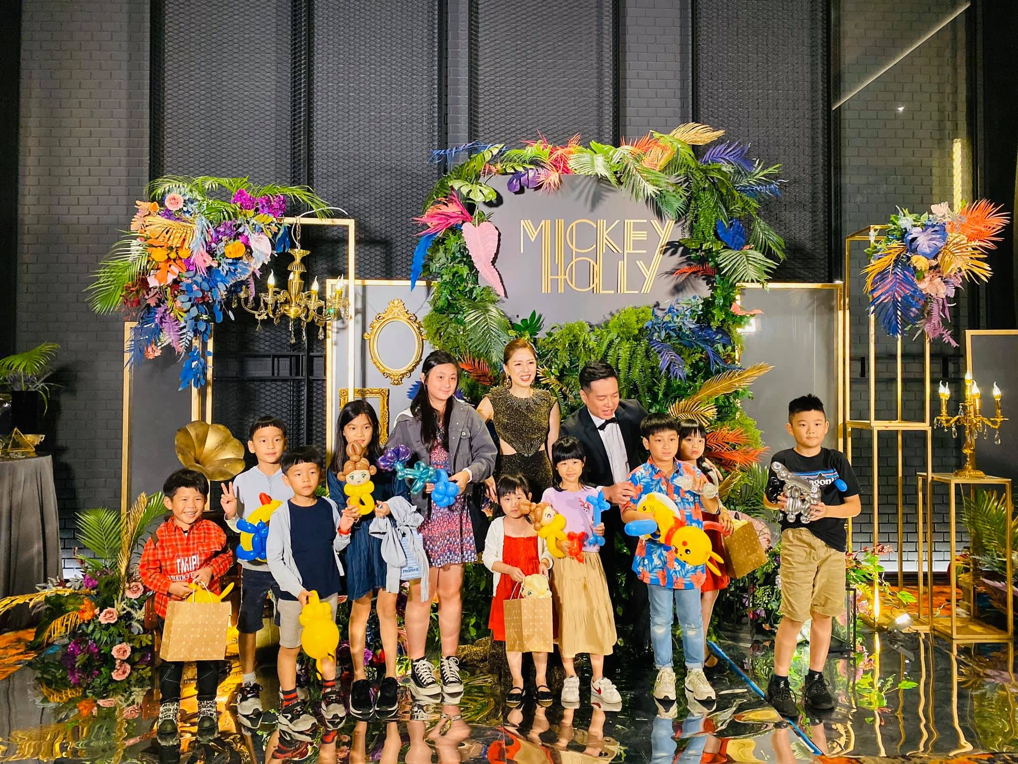 婚宴背板前，一排小朋友拿著造型氣球和新人大合照