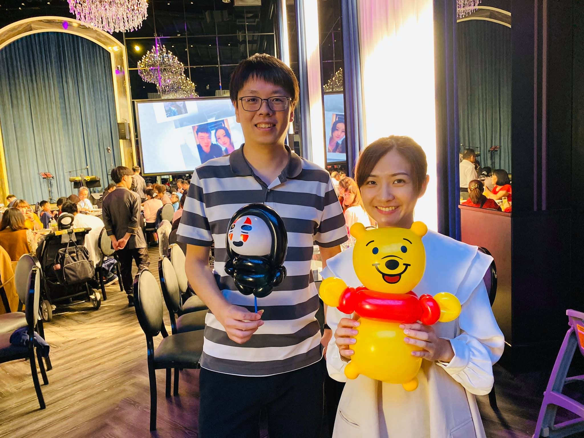 一對賓客拿著黑色面具造型與小熊維尼氣球