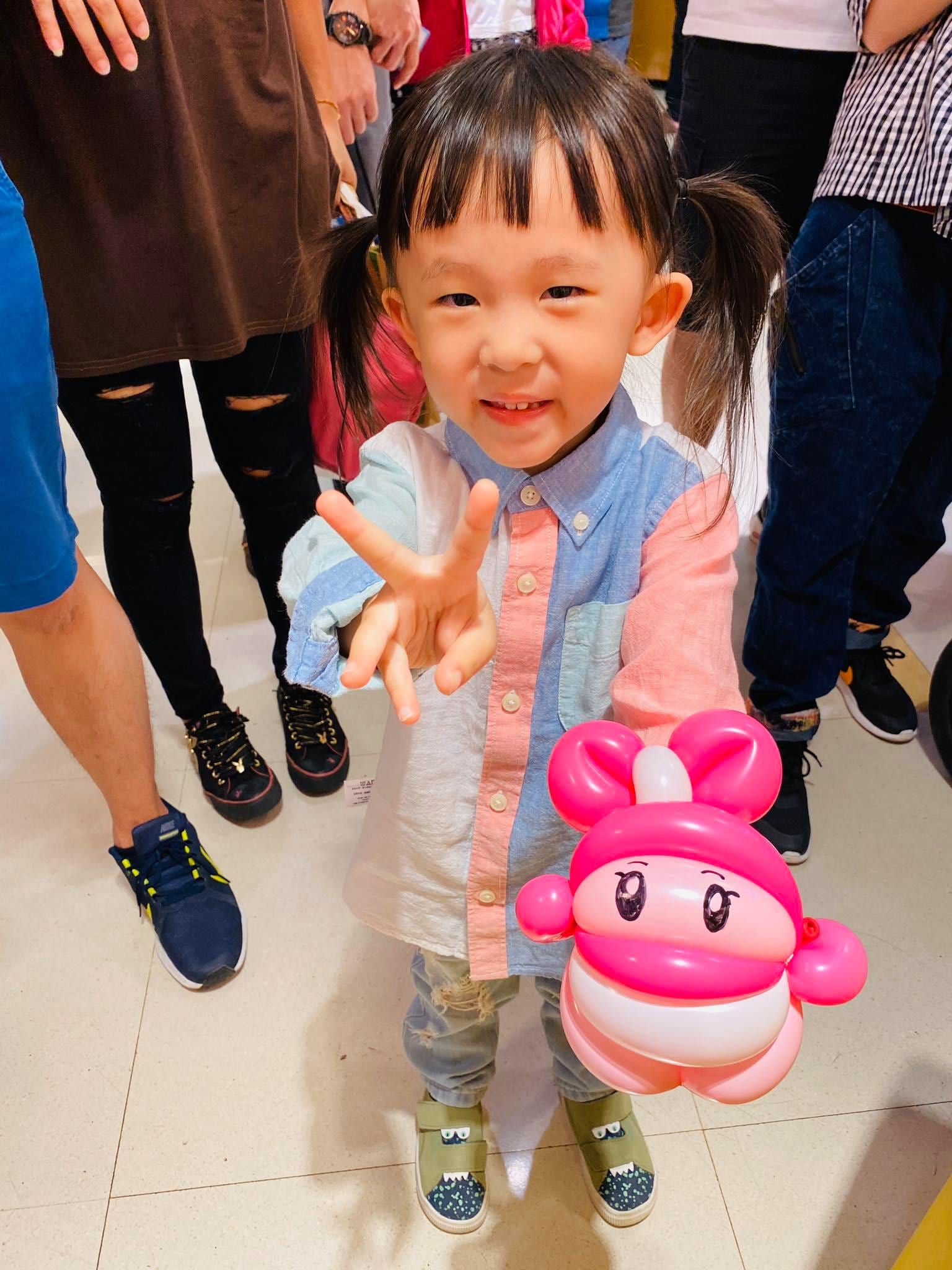 綁雙馬尾的小女孩拿著粉紅色兔子造型氣球