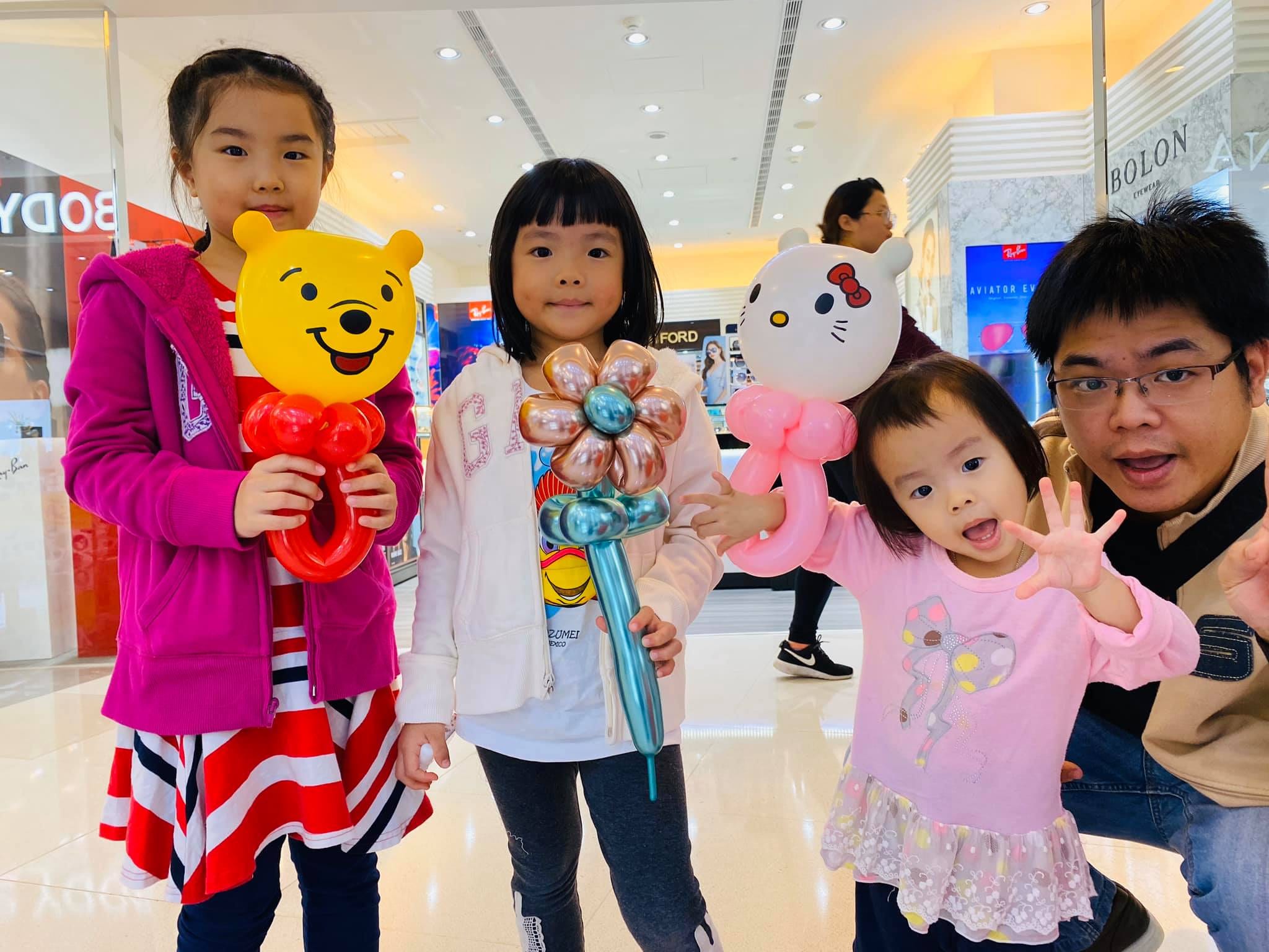 三個女孩拿著小熊維尼、金屬花朵與 Hello Kitty 造型氣球