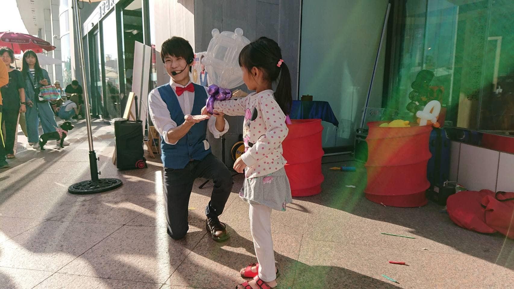 我單膝跪地,把白色造型氣球交給小女孩