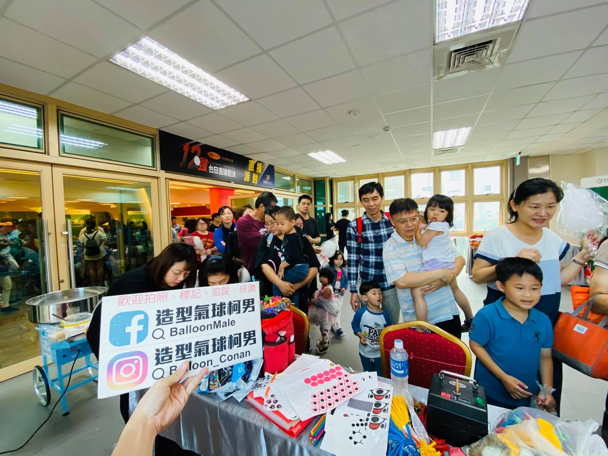 攤位前的號碼登記與排隊人潮,舉起的牌子印著造型氣球柯男
