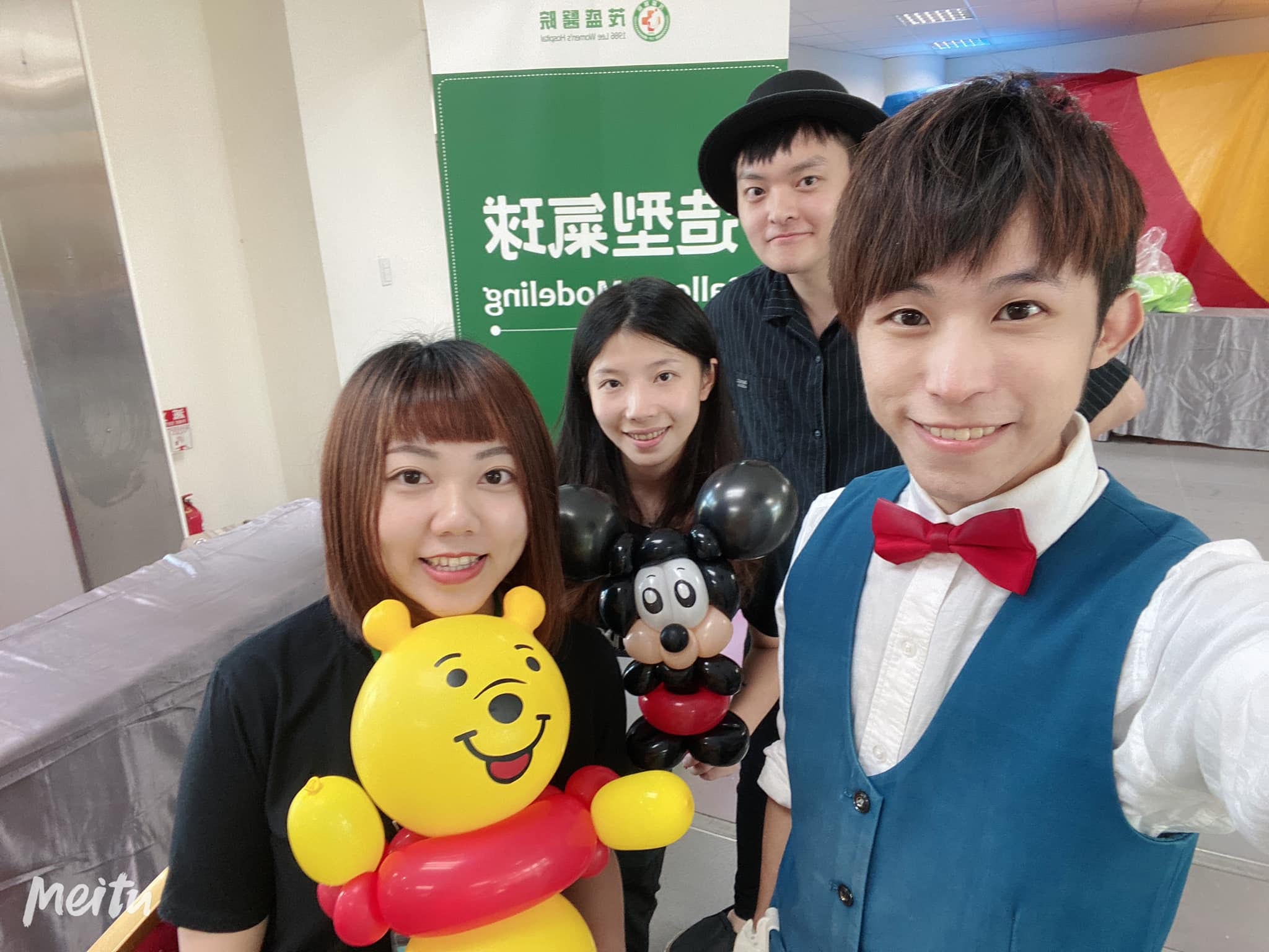 台中親子活動的造型氣球攤位前,我和工作人員拿著小熊維尼與米奇自拍