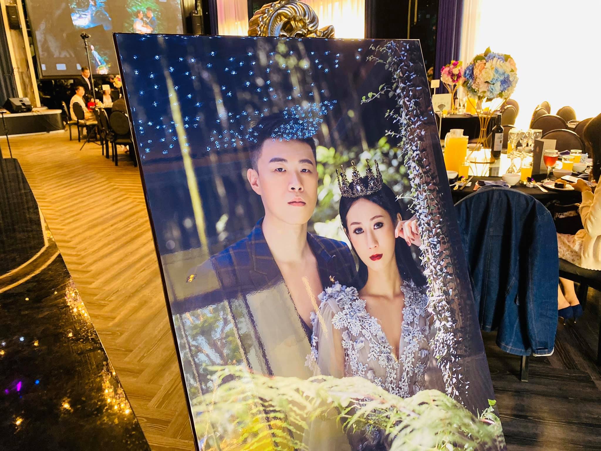 婚宴會場入口的新人婚紗照立牌，後方是宴客桌