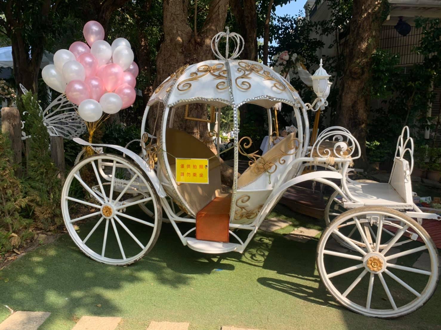 戶外草地上的白色南瓜馬車,旁邊綁著一束粉白氣球