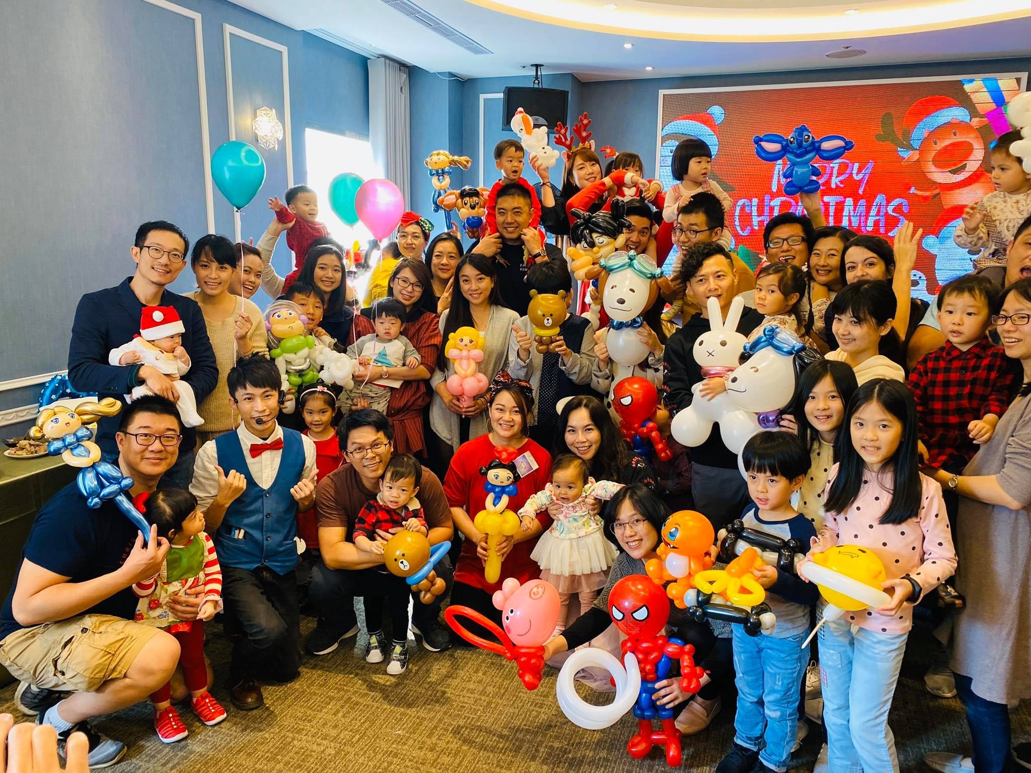 MERRY CHRISTMAS 背板前，大人小孩拿著造型氣球大合照