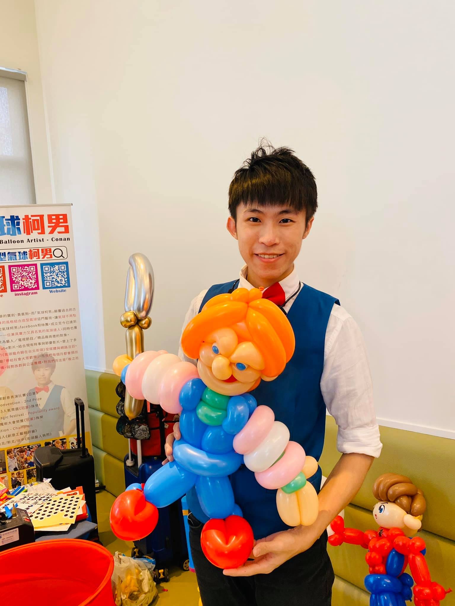 我在攤位前抱著橘色頭髮、條紋衣服的恰吉造型氣球