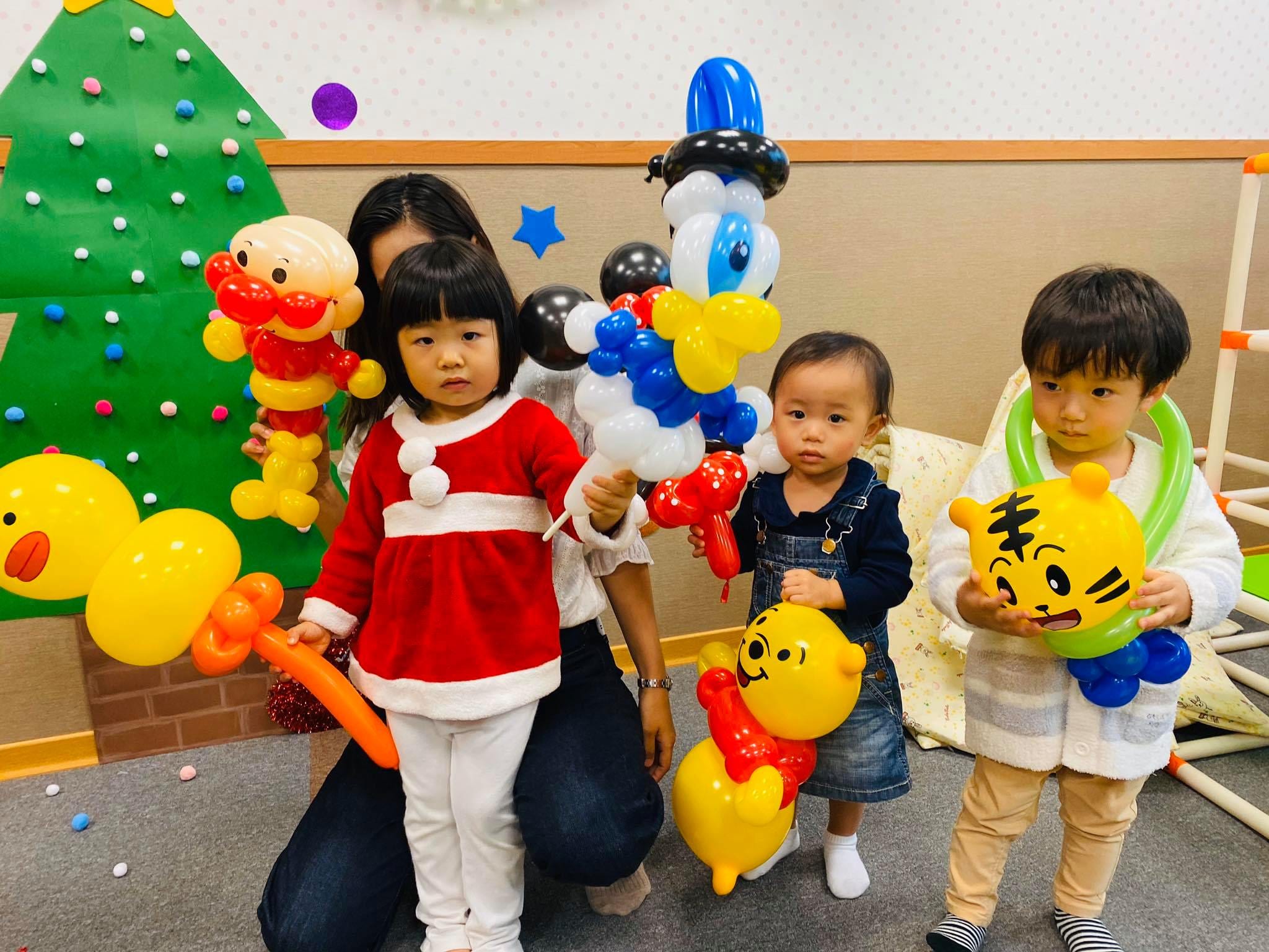 聖誕樹前的孩子們拿著麵包超人、唐老鴨與巧虎造型氣球