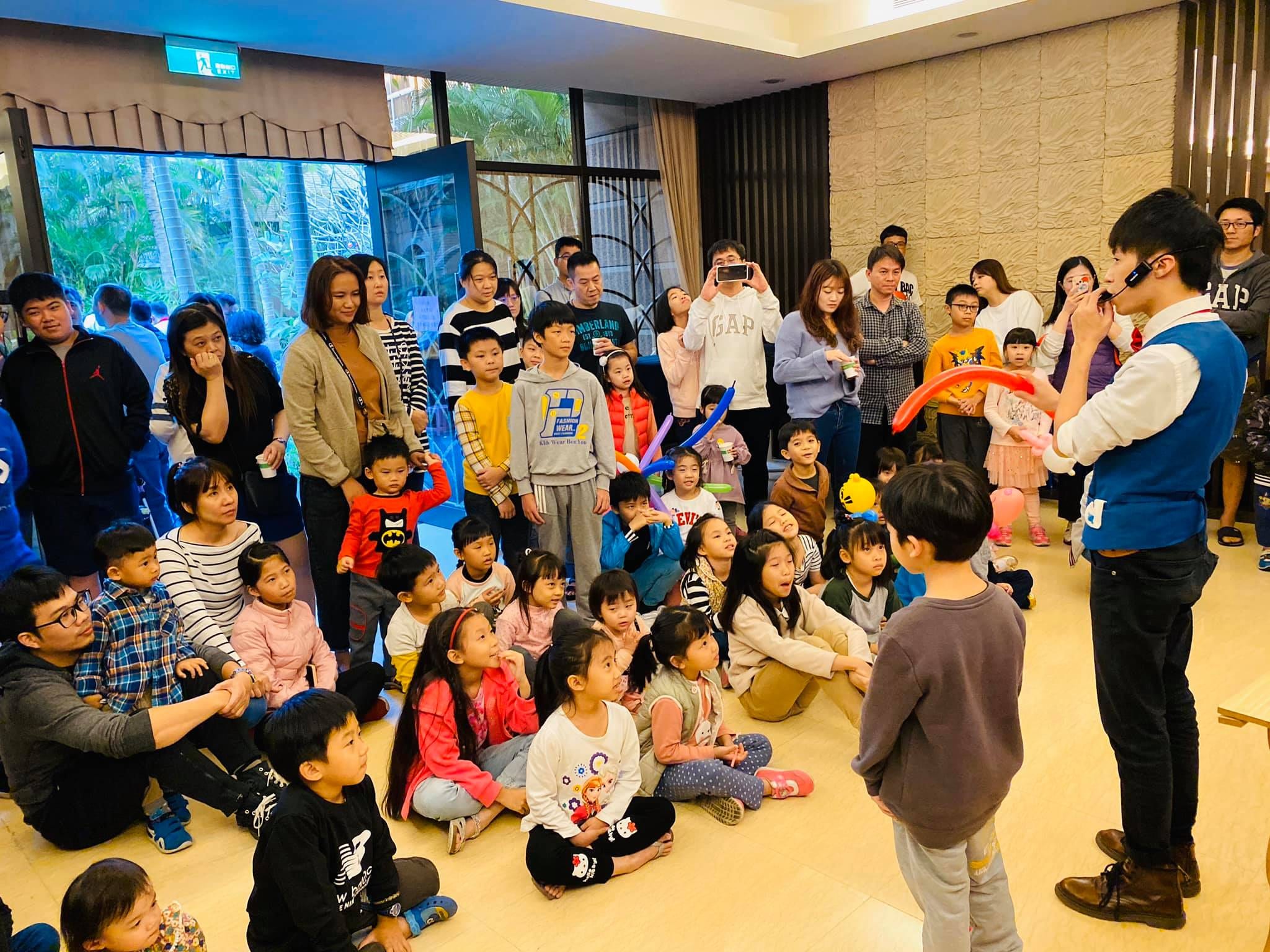 坐滿地板的親子觀眾前，男孩站上台和我一起表演