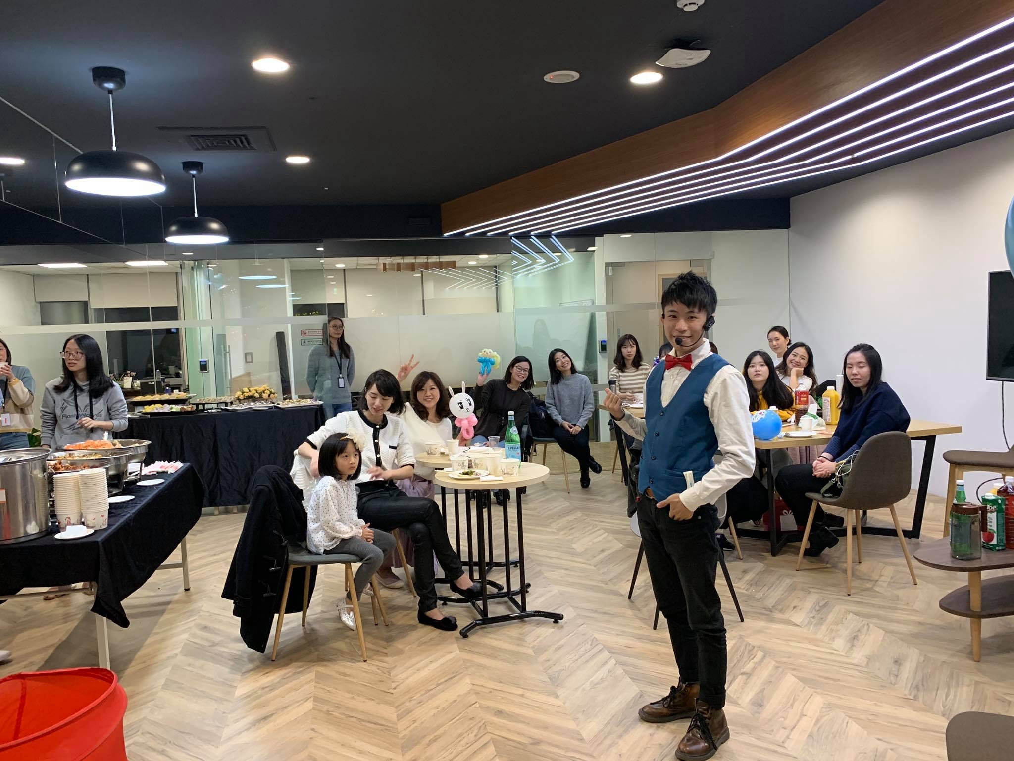 辦公室交誼區的員工坐著看表演，後方擺著自助餐