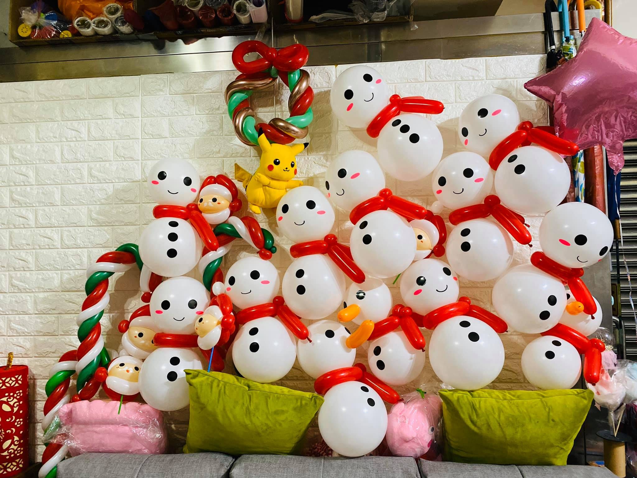 沙發上堆滿圍紅圍巾的雪人氣球，夾雜聖誕老人、皮卡丘與花圈