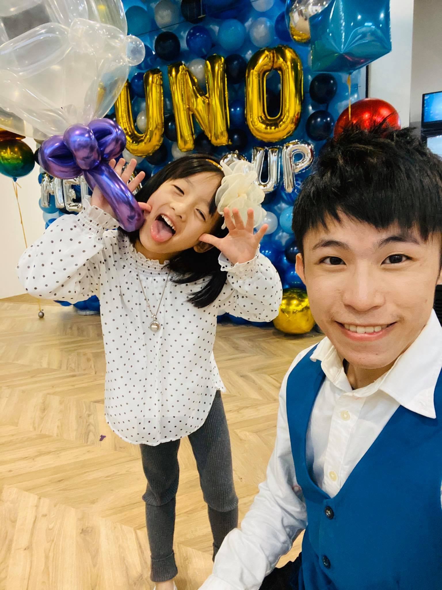我和做鬼臉的小女孩自拍，她手上拿著紫色造型氣球