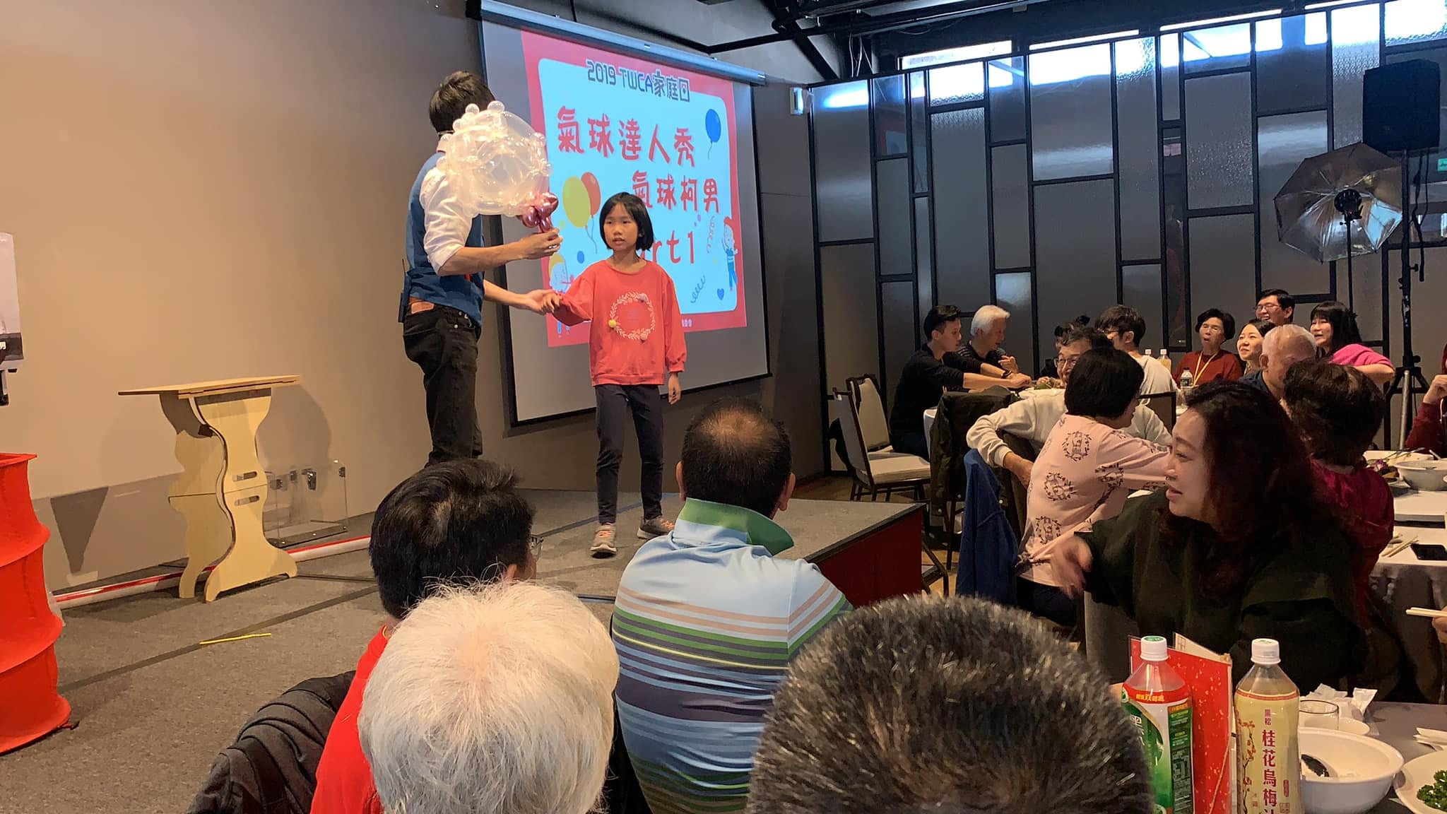 家庭日舞台上，穿粉紅外套的小女孩上台協助表演