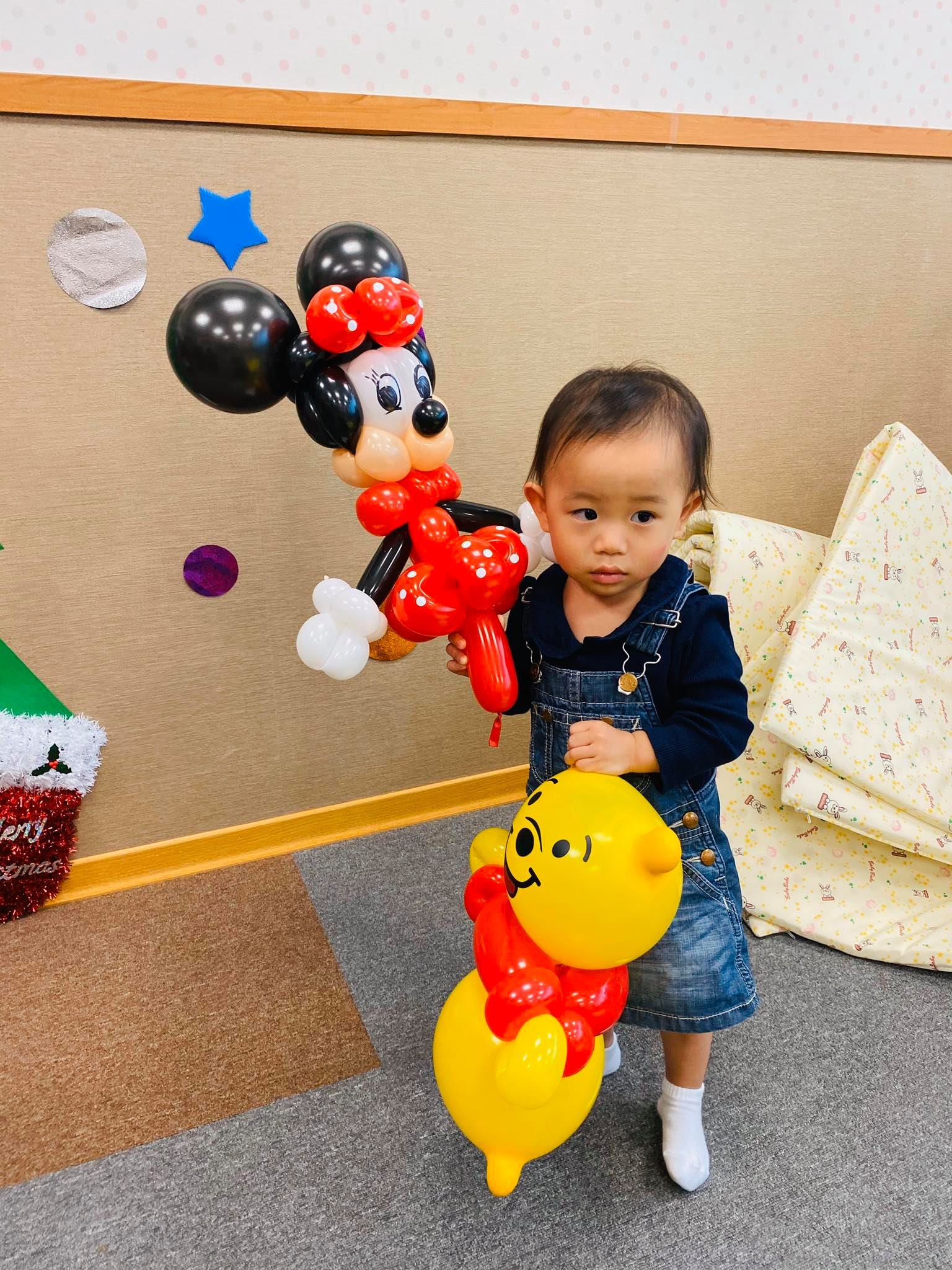 穿吊帶裙的小小孩拿著米妮與小熊維尼造型氣球