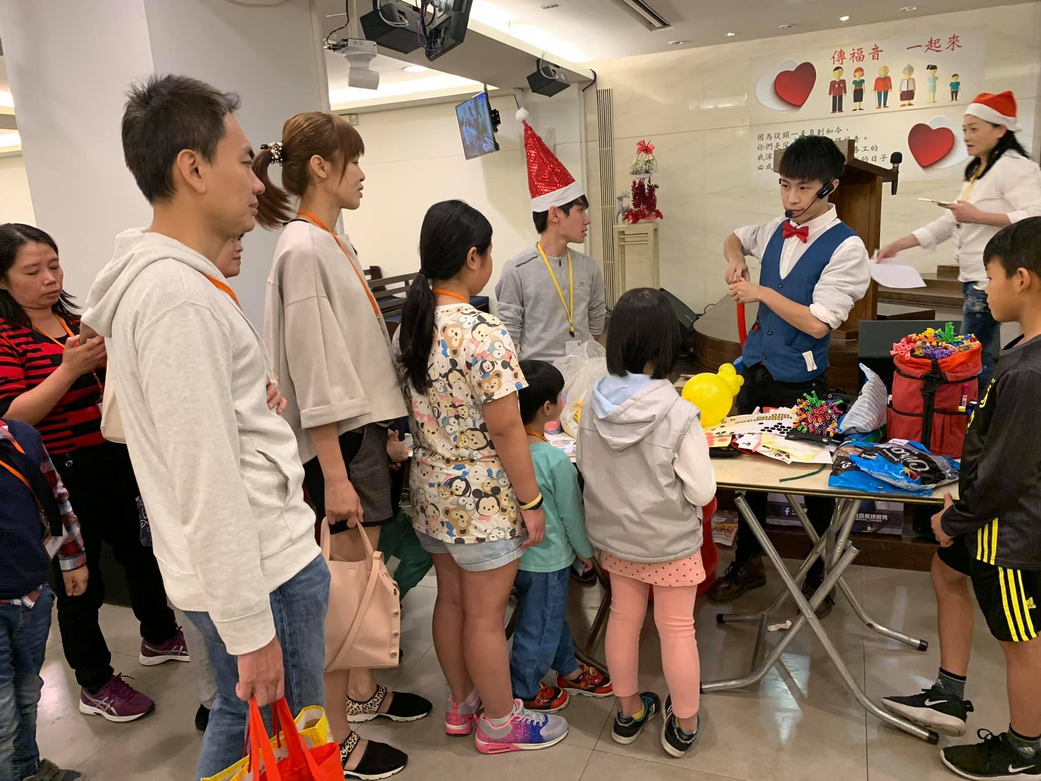 教會活動室裡，我在折氣球桌前，家長和孩子排隊等候