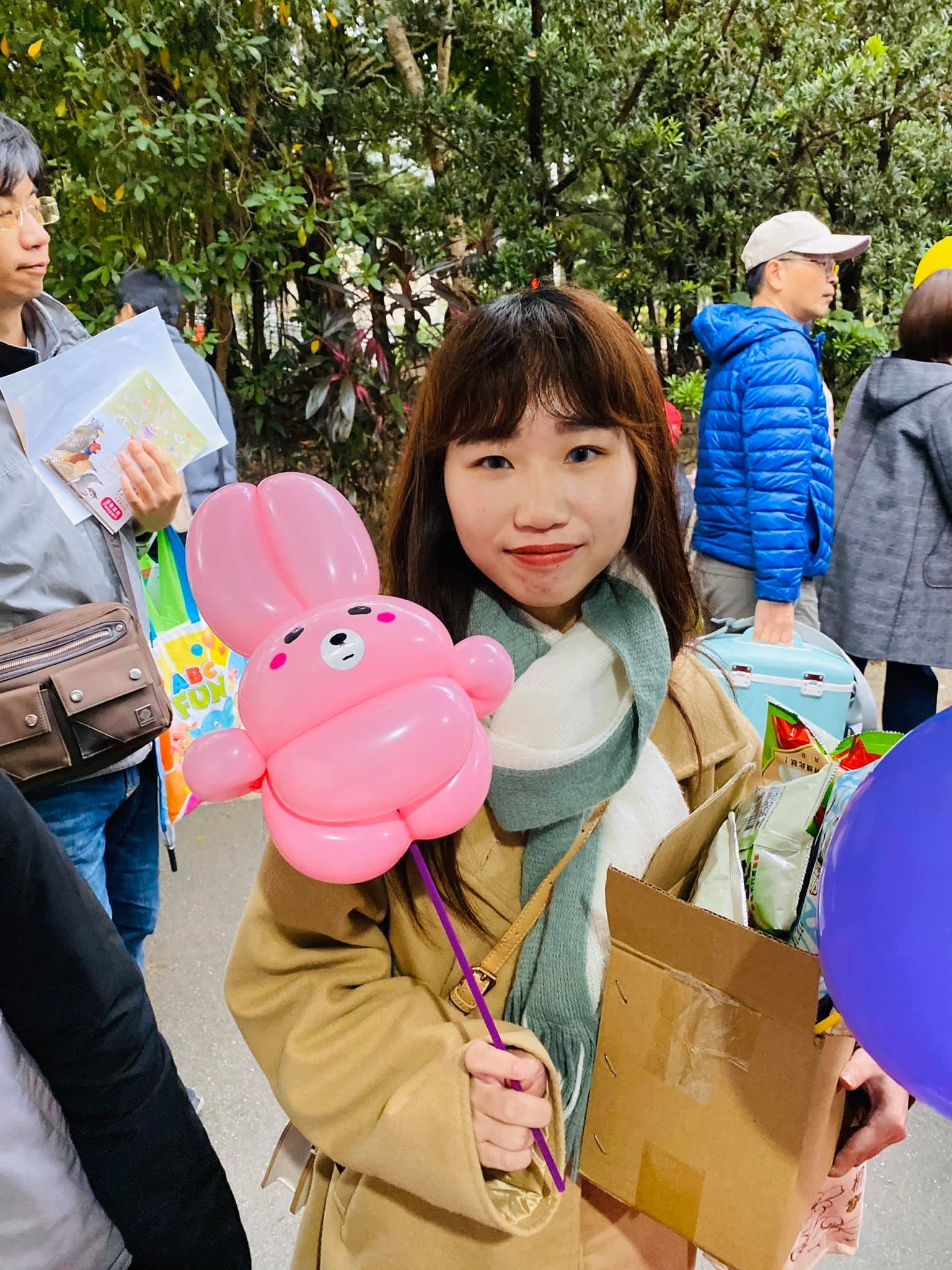圍圍巾的女生拿著粉紅色兔子手持棒
