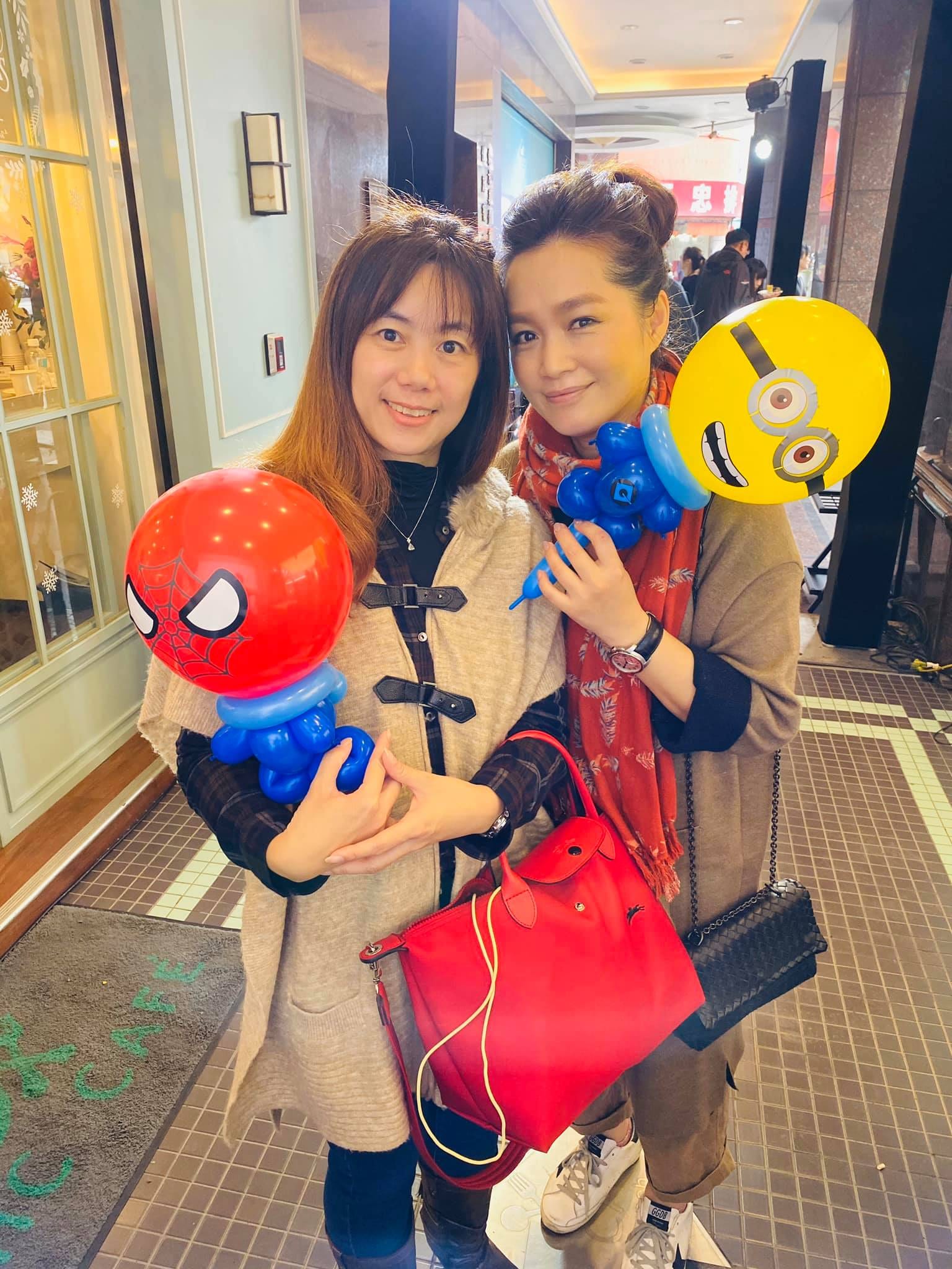 兩位女生分別拿著蜘蛛人與小小兵造型氣球