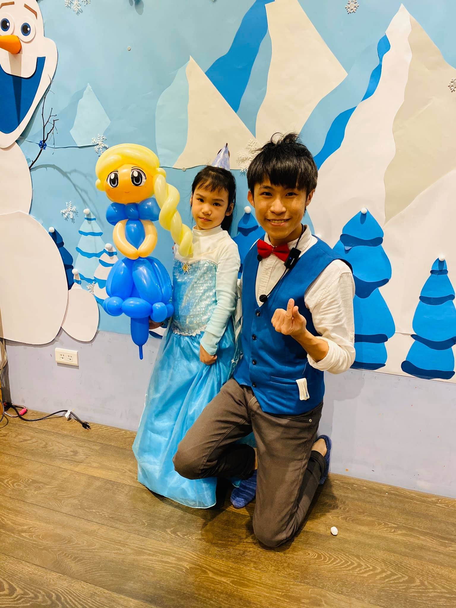 雪寶壁畫前，穿艾莎禮服的小女孩拿著艾莎造型氣球和我合照