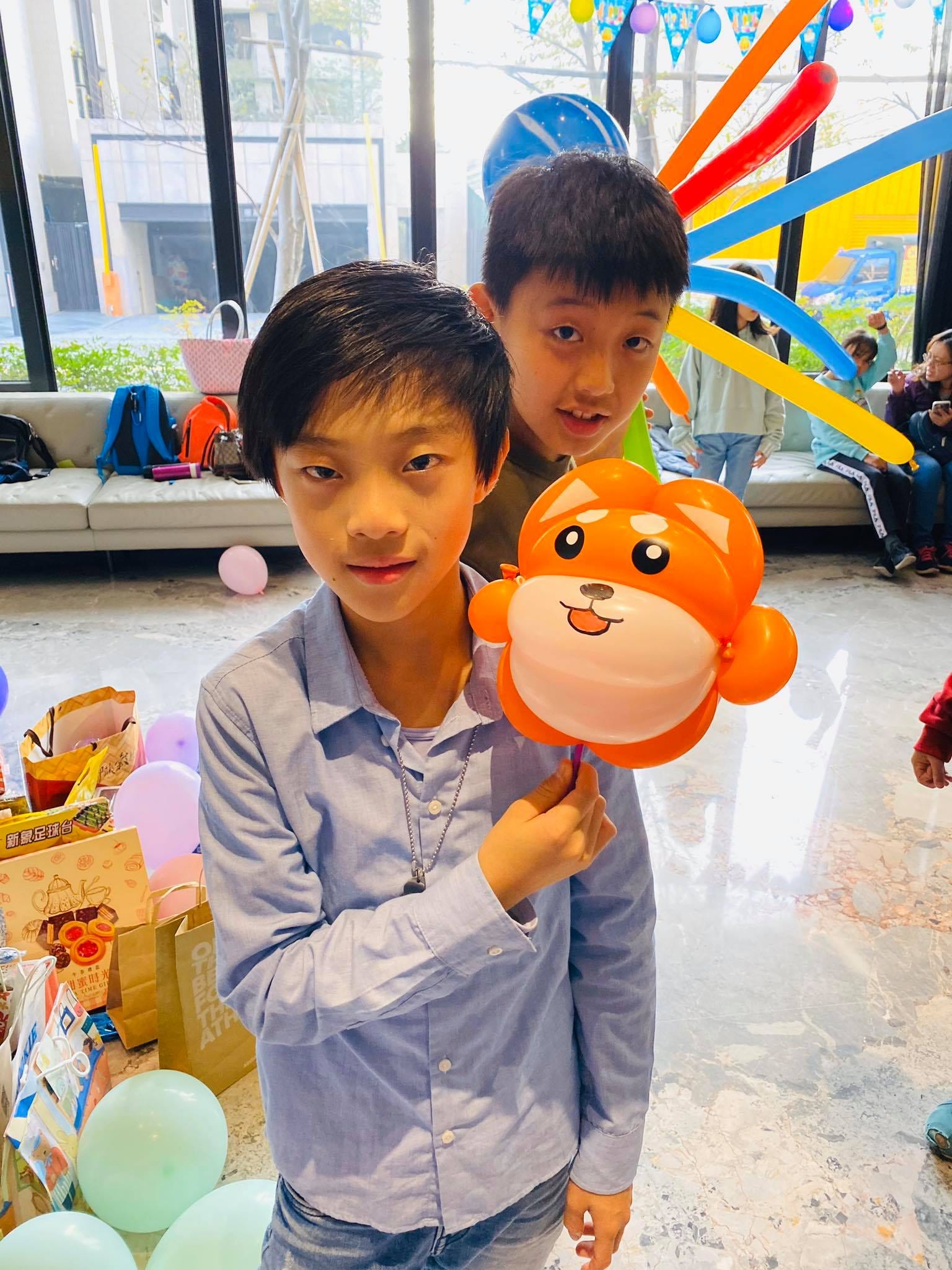 穿藍色襯衫的男孩拿著橘色圓臉小動物造型手拿棒