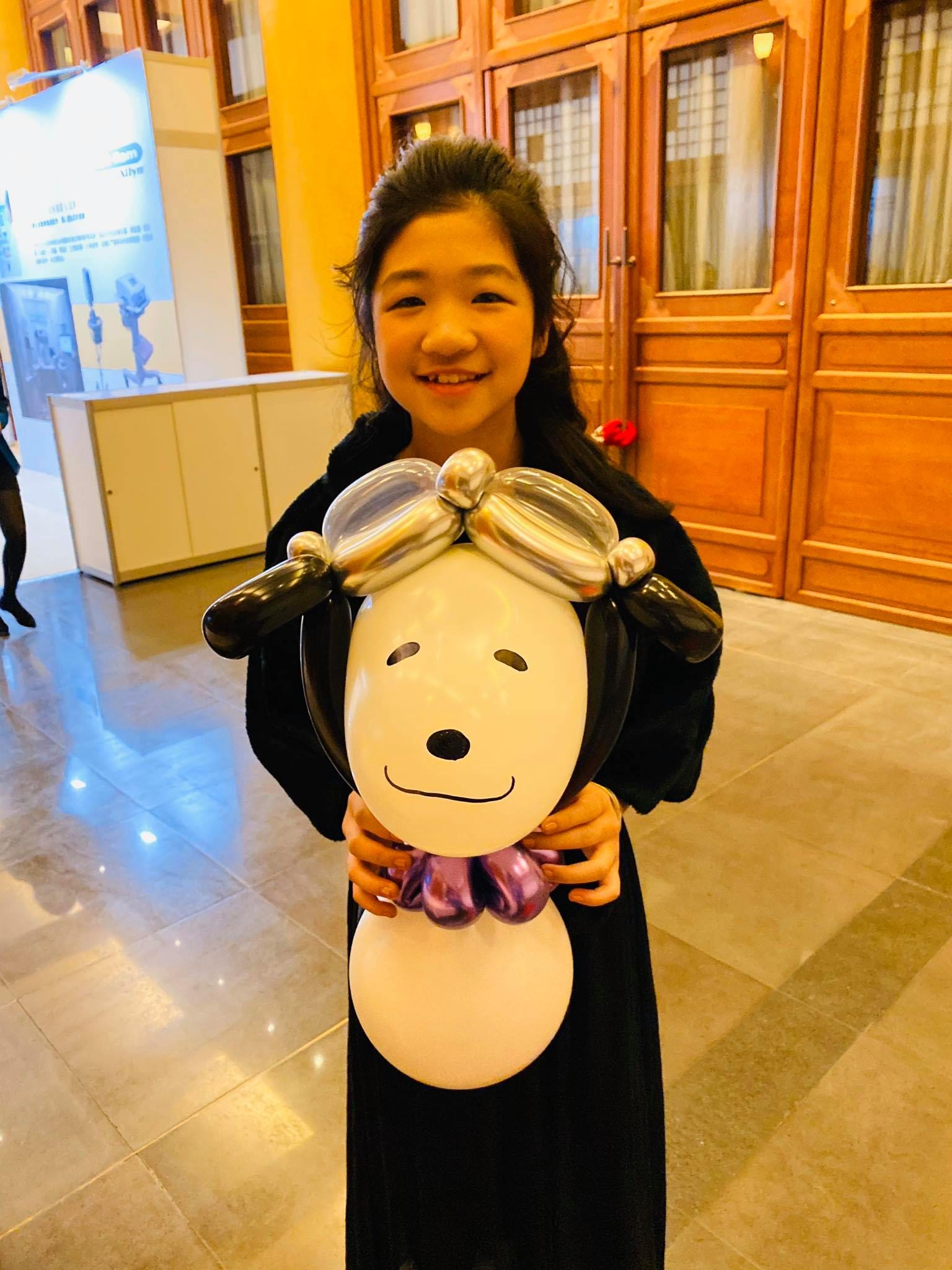 女孩抱著黑色耳朵、白色身體的大型小狗氣球