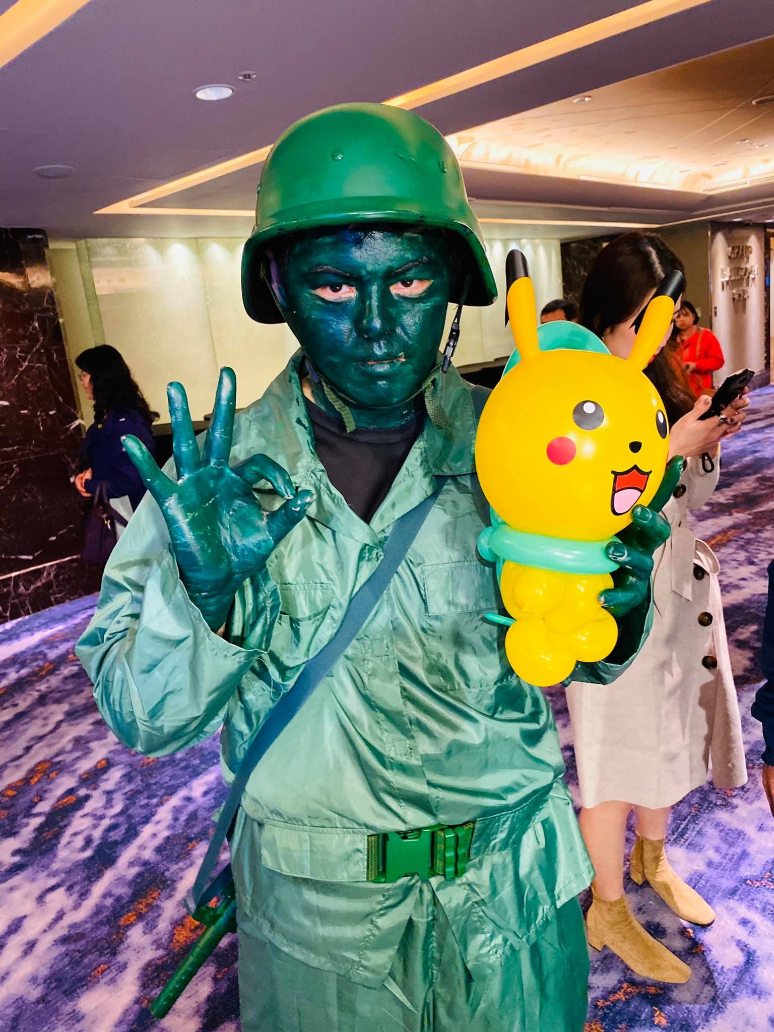 全身綠色的小綠兵變裝者，拿著皮卡丘氣球比 OK