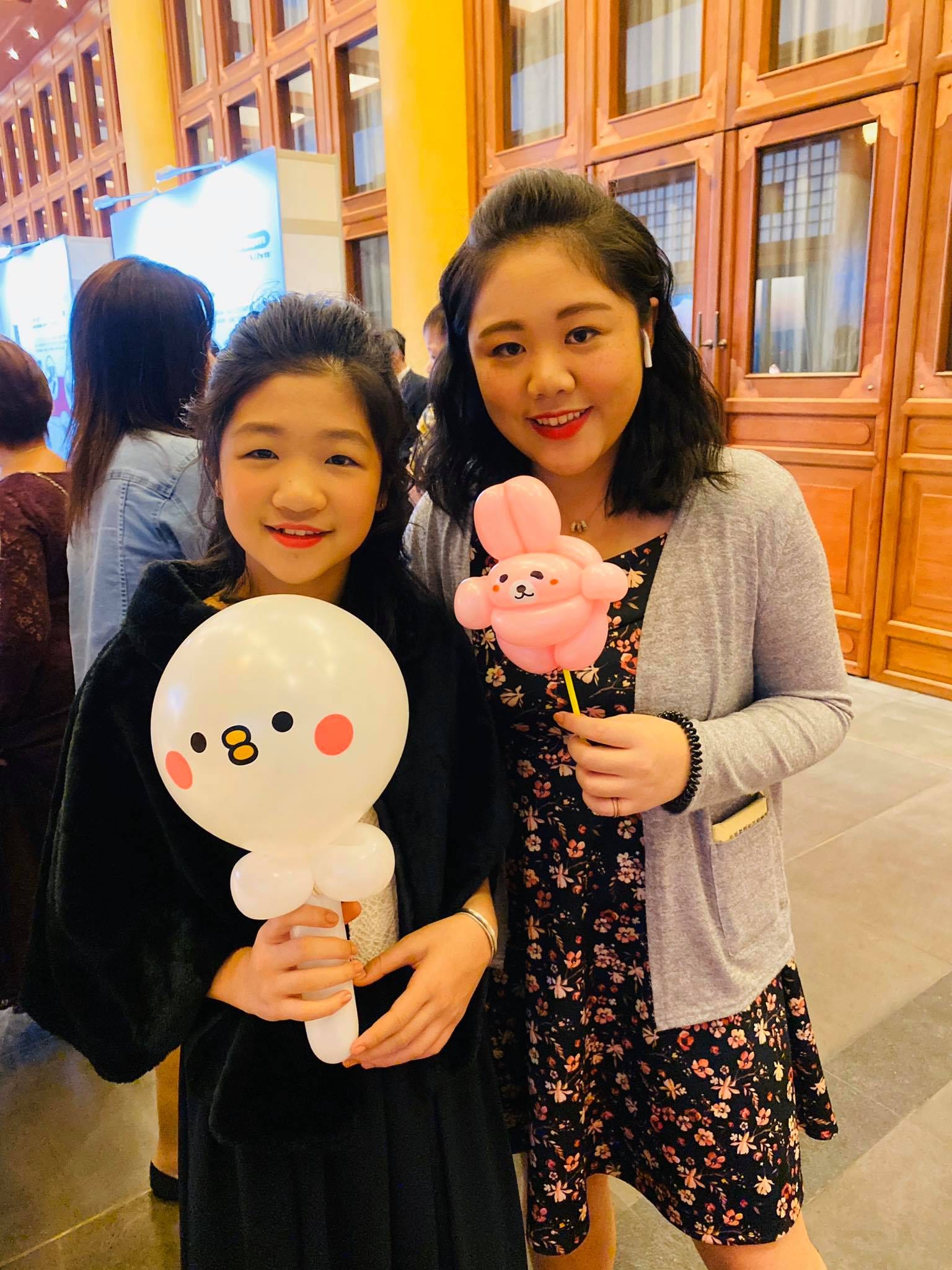 媽媽和女兒拿著白色小鳥與粉紅兔子造型氣球合照