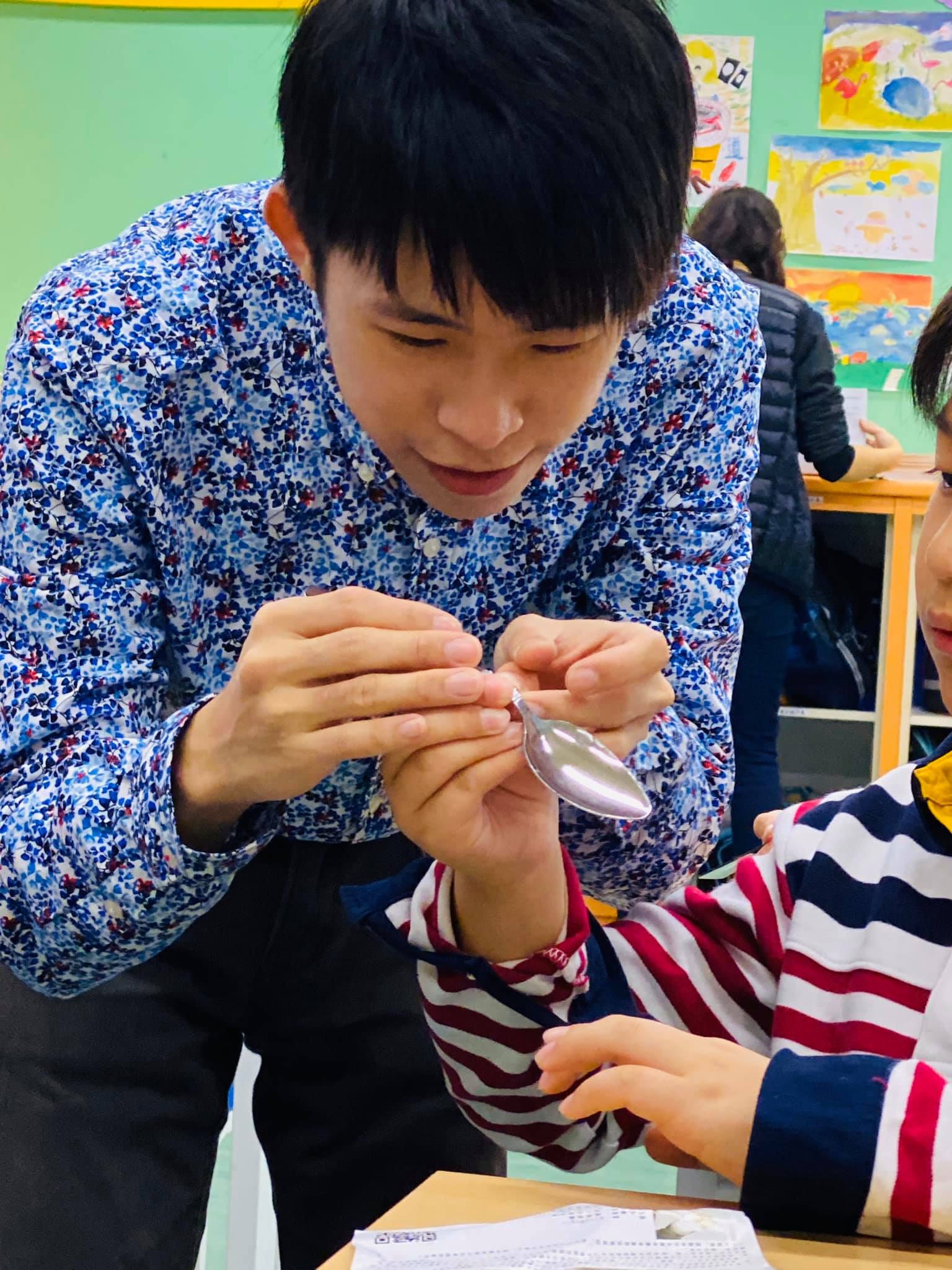 穿花襯衫的我拿著湯匙，在學生面前示範魔術