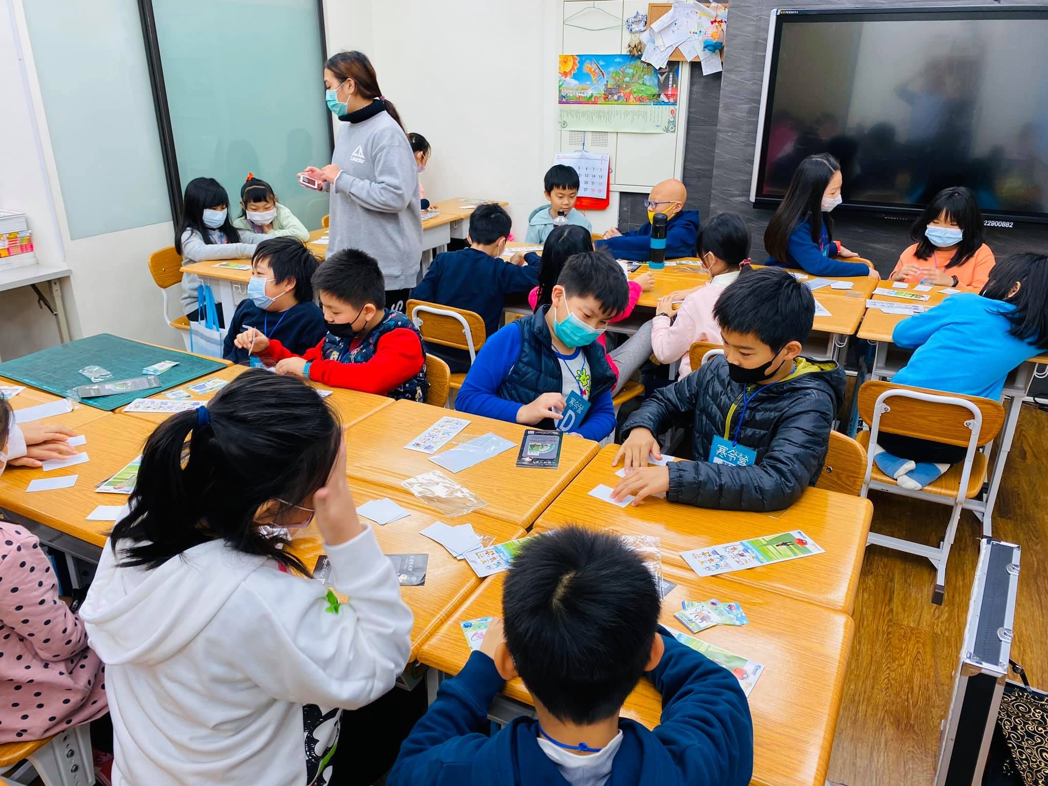 補習班教室裡學生分組坐在課桌前,練習桌上的紙牌魔術
