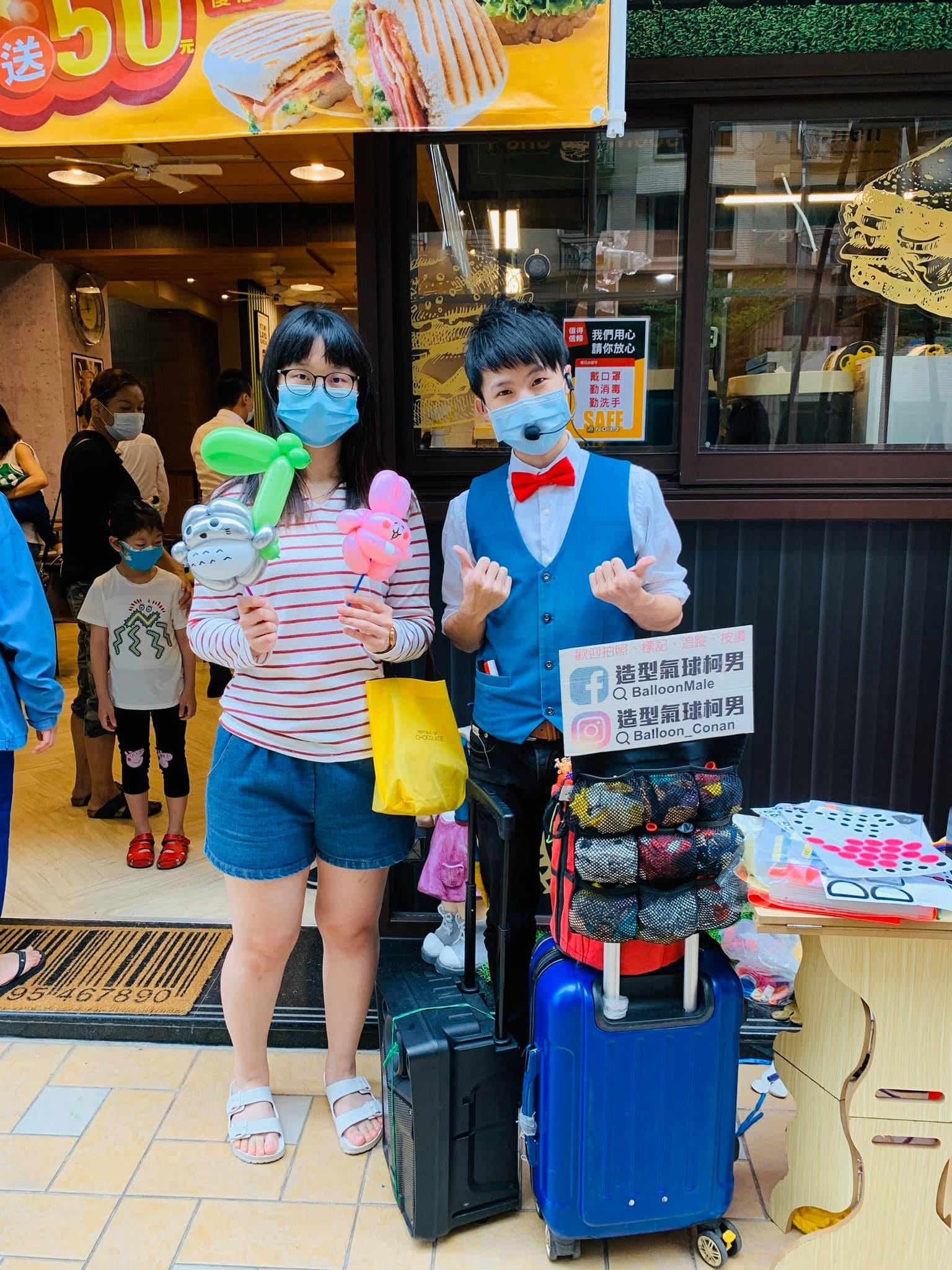 客人拿著兩支氣球和戴口罩的我在攤位旁比讚合照