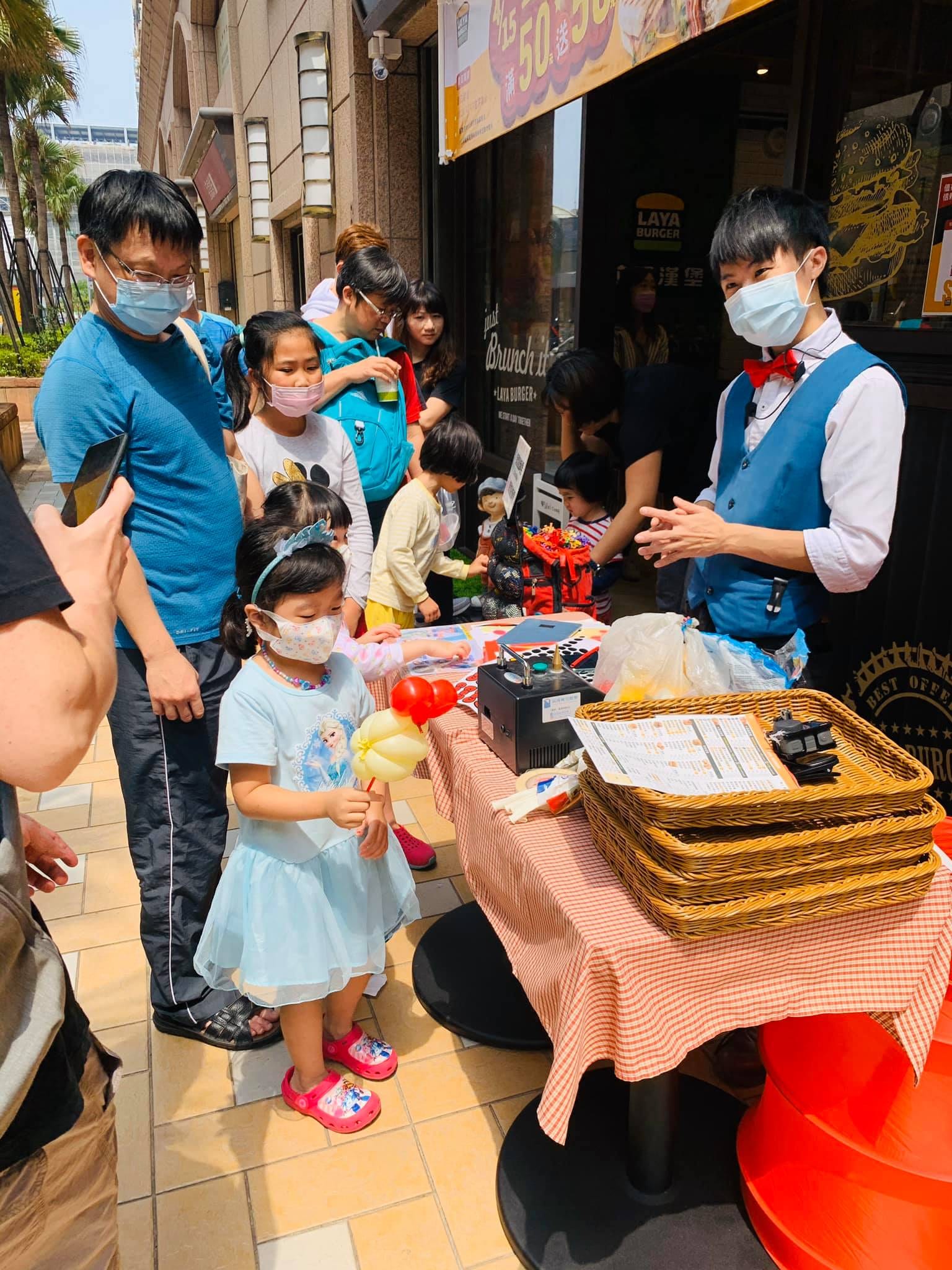 穿淺藍公主裙的小女孩拿著黃色氣球站在攤位前