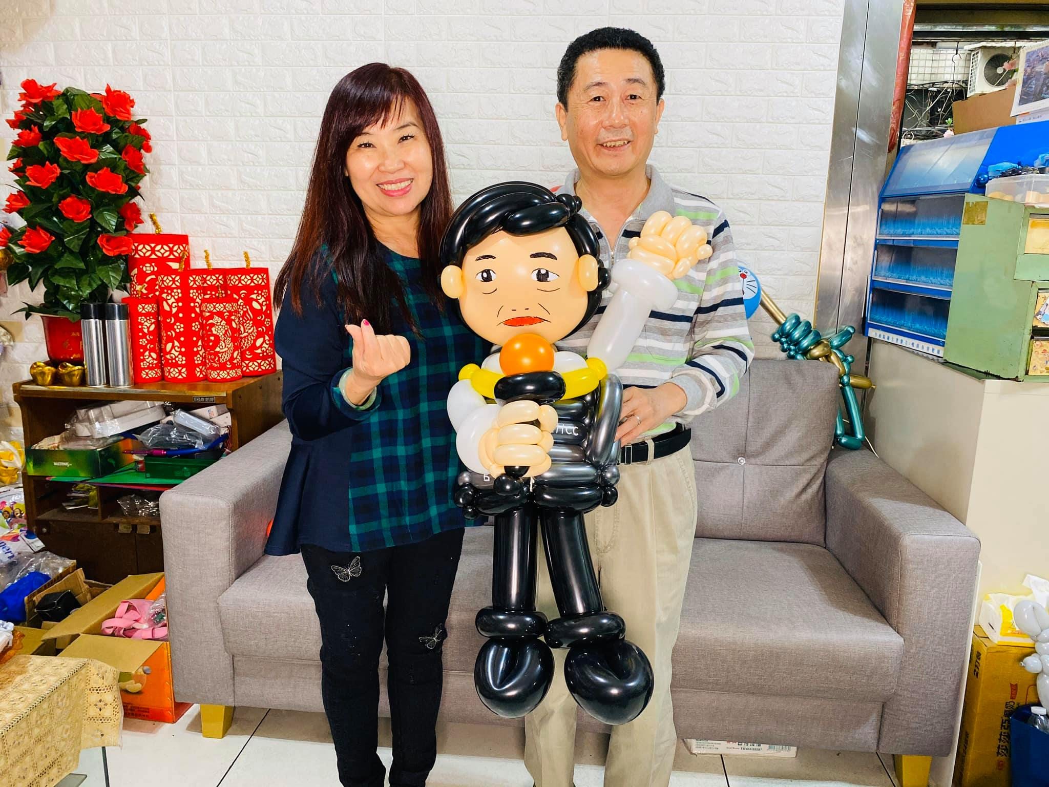 柯爹與一位家人在沙發前抱著陳時中造型氣球合照