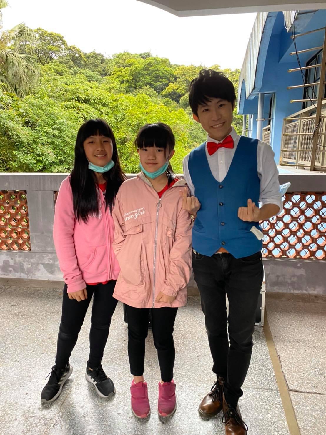 兩位穿粉紅外套的女學生在走廊欄杆前和我合照