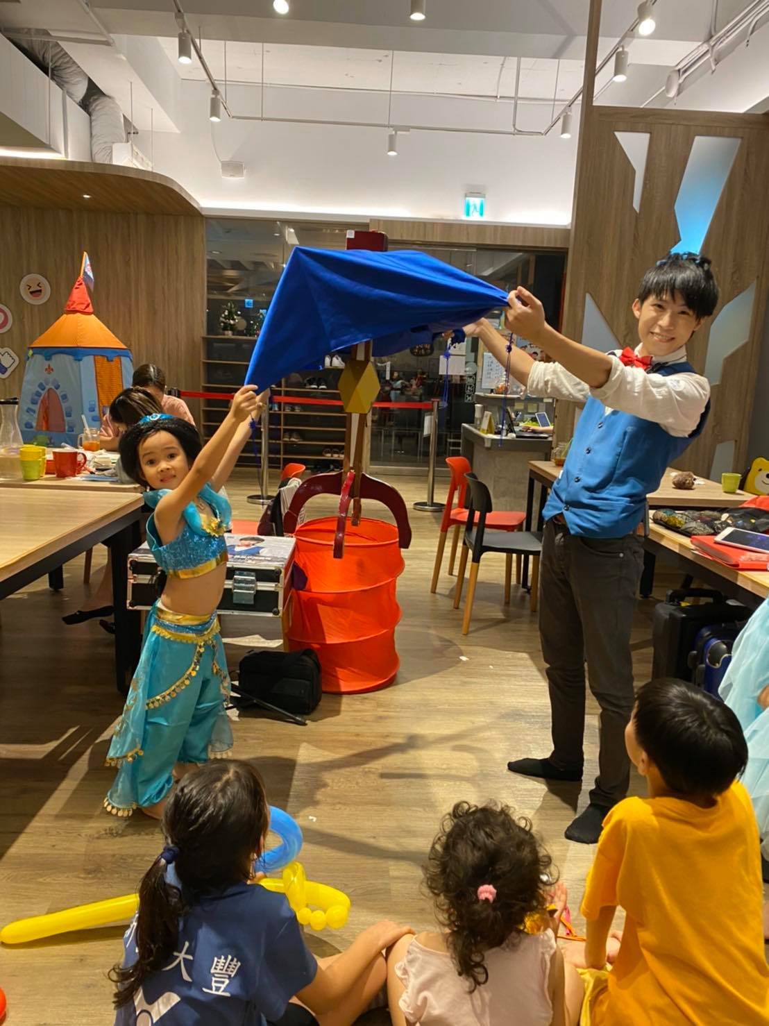 藍色公主裝女孩上台幫忙拉起藍布，一起完成道具魔術