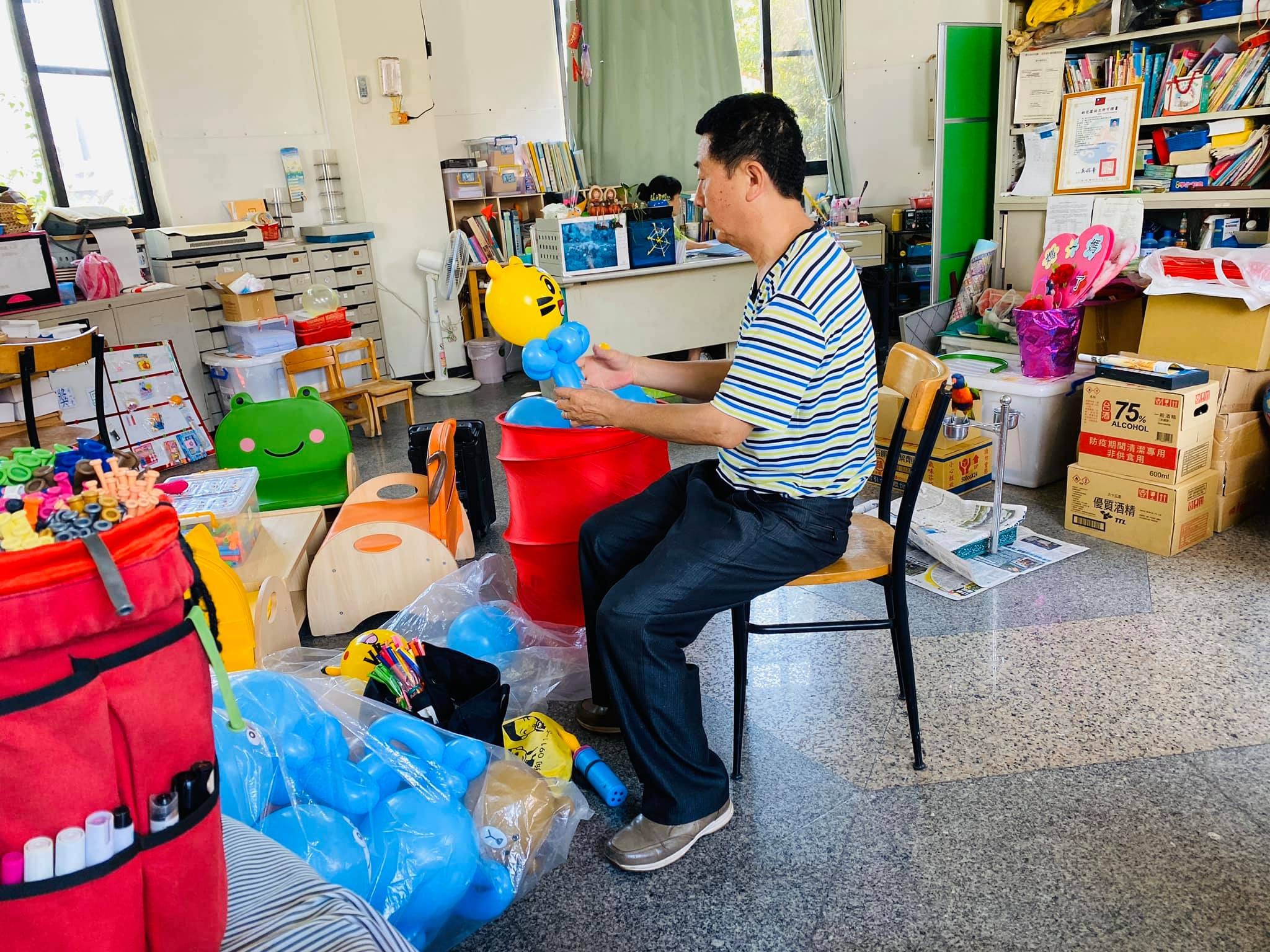 柯爹坐在幼兒園辦公室裡組裝巧虎造型氣球的身體