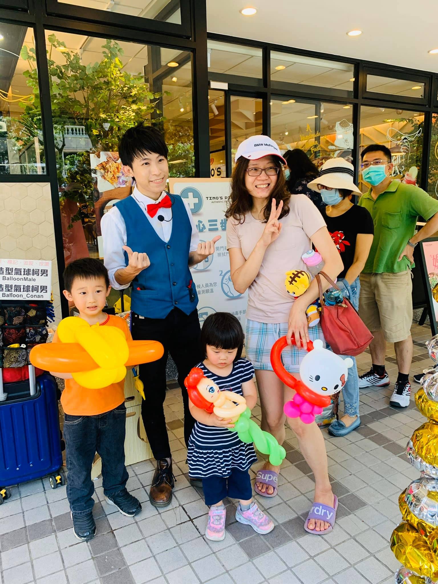 一家人拿著 Hello Kitty、小美人魚與寶劍造型氣球合照
