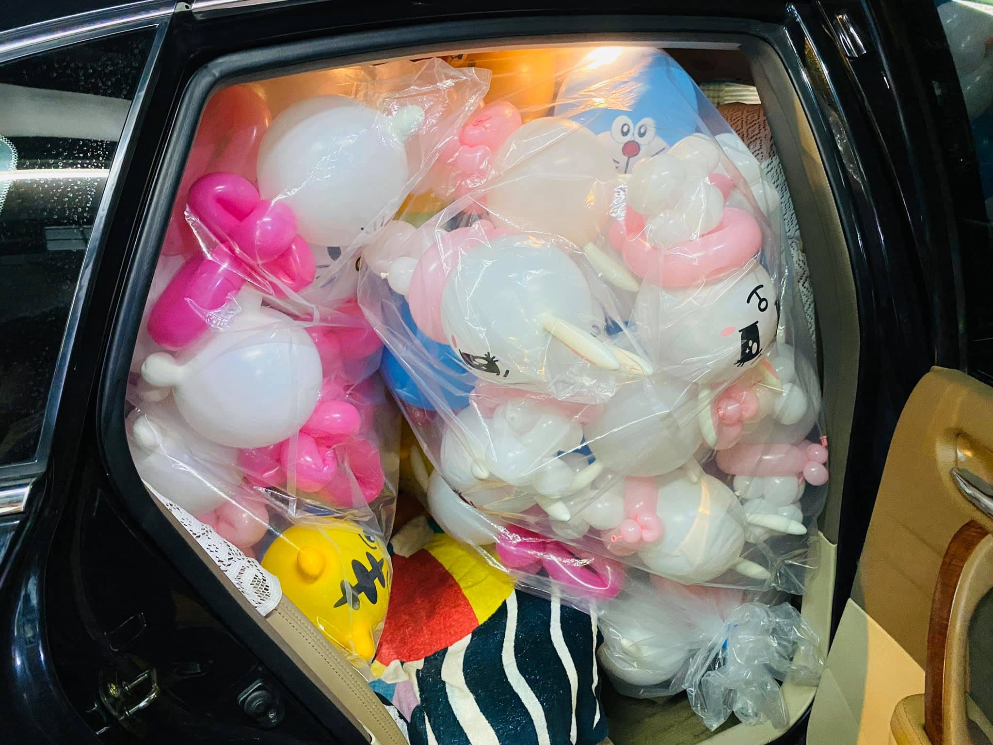 轎車後座塞滿整袋造型氣球，可以看到哆啦A夢和白色兔子