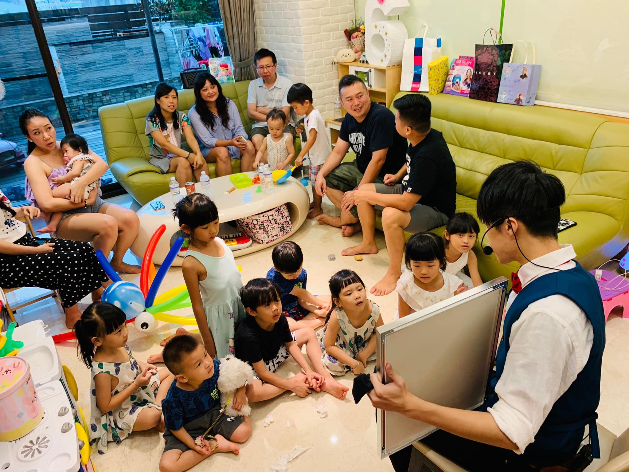 客廳裡小朋友坐地板、大人坐沙發一起看魔術表演