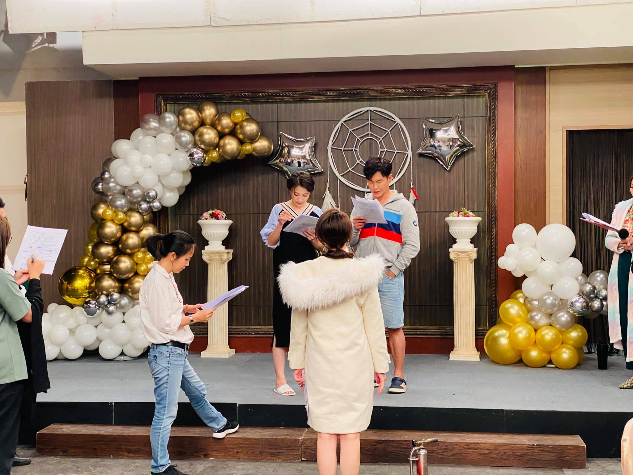 炮仔聲婚禮場景，金銀白氣球拱前演員拿劇本排練