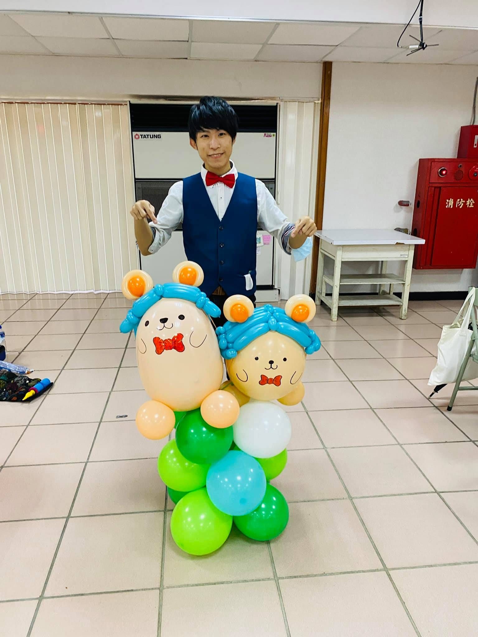藍色頭髮、紅領結的兩隻小熊吉祥物氣球，站在綠白藍底座上