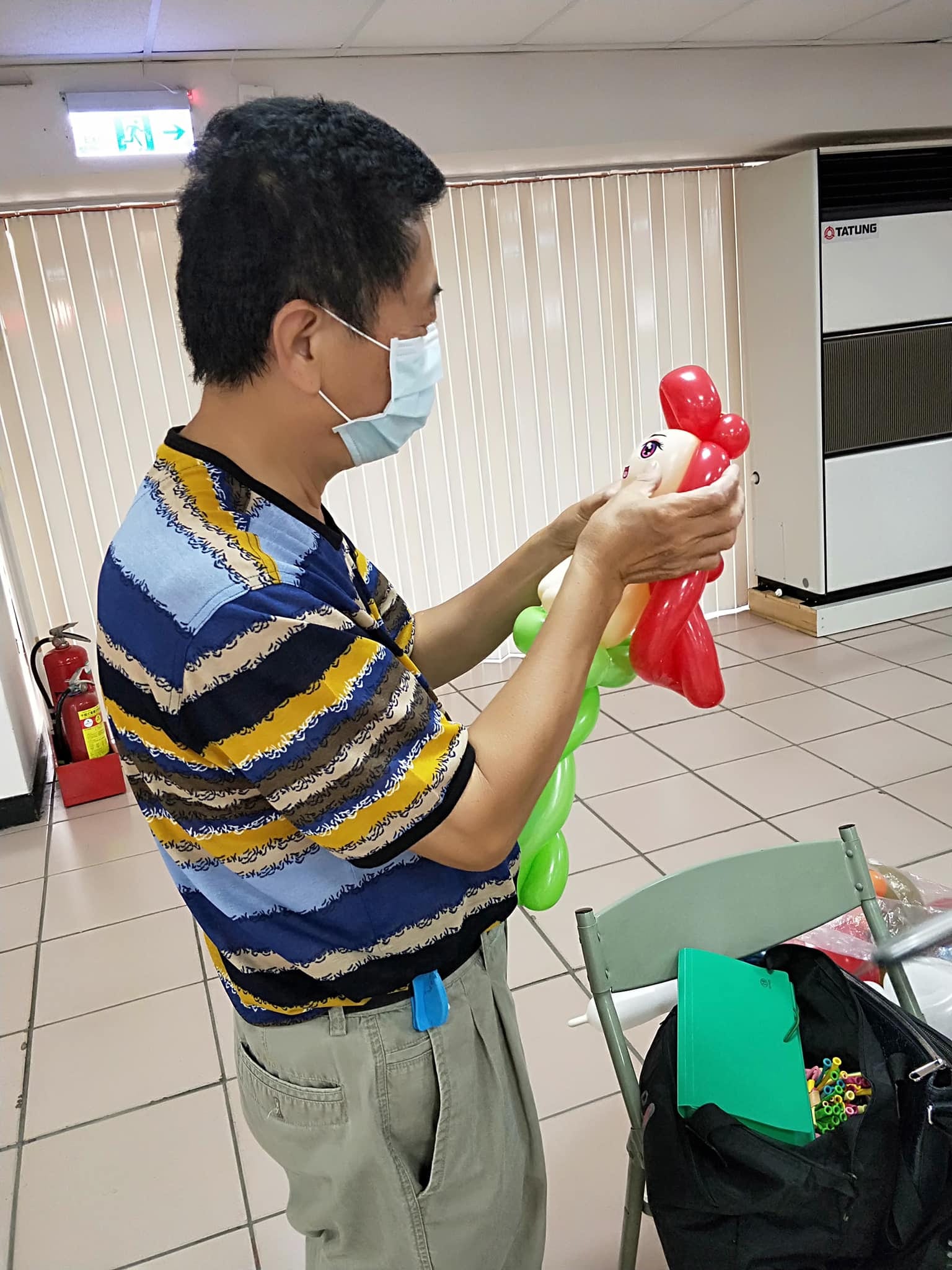 戴口罩的長輩手拿紅髮綠尾巴的小美人魚造型氣球