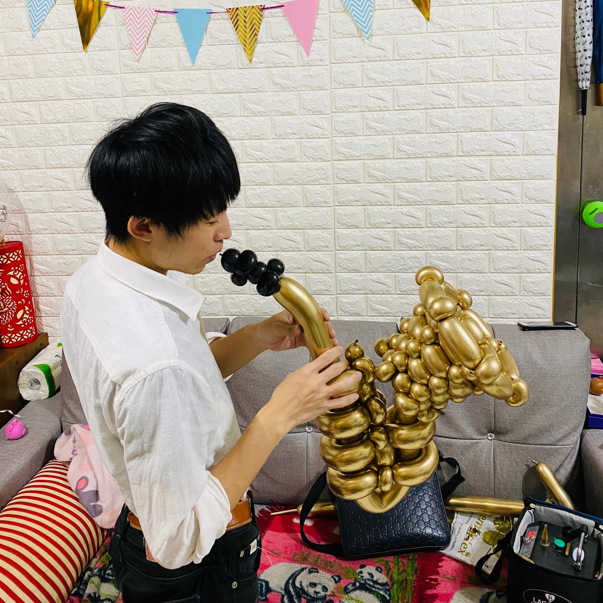 白襯衫男子在沙發前假裝吹奏金色薩克斯風氣球