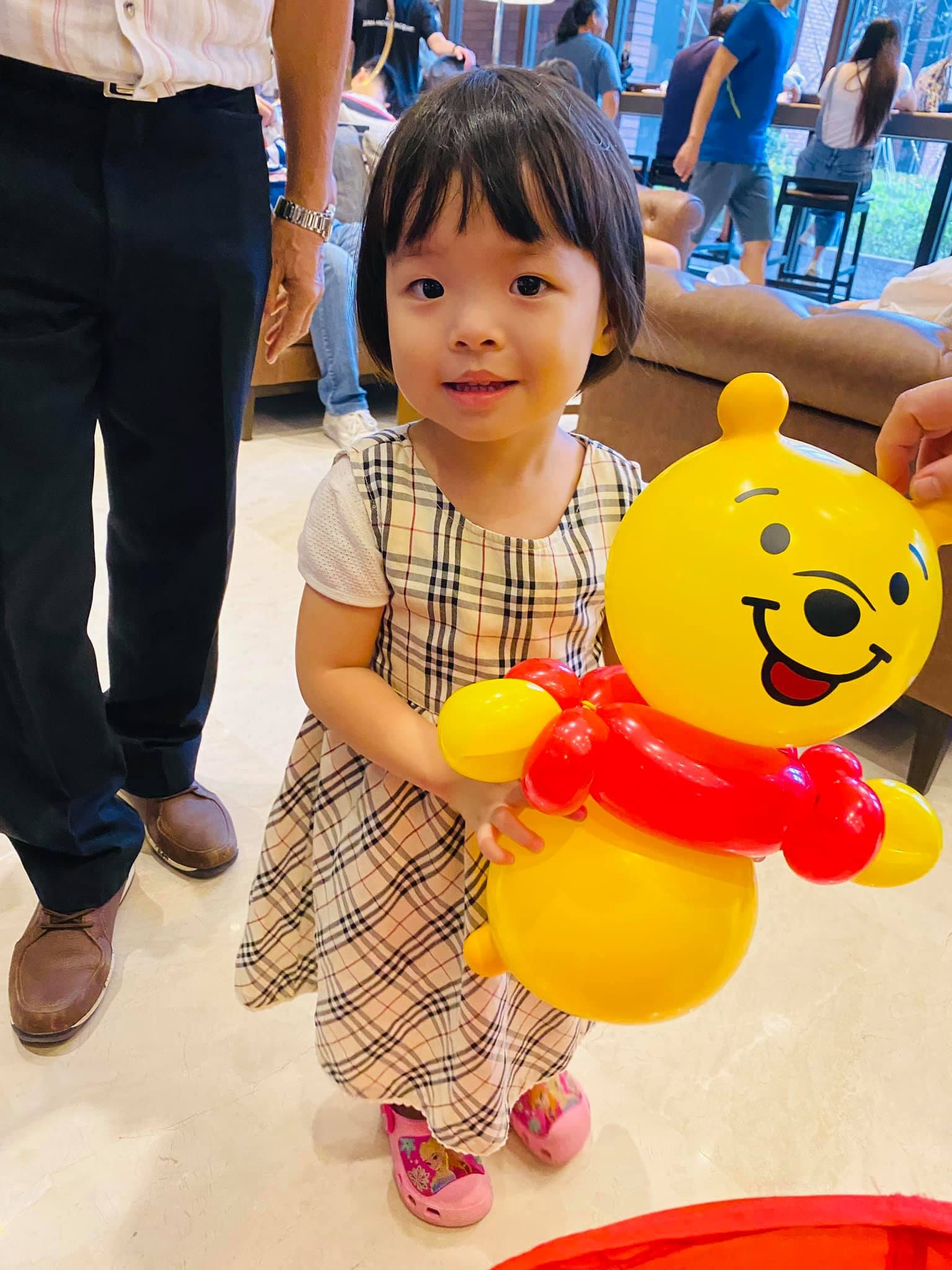 格紋洋裝小女孩抱著紅衣小熊維尼造型氣球