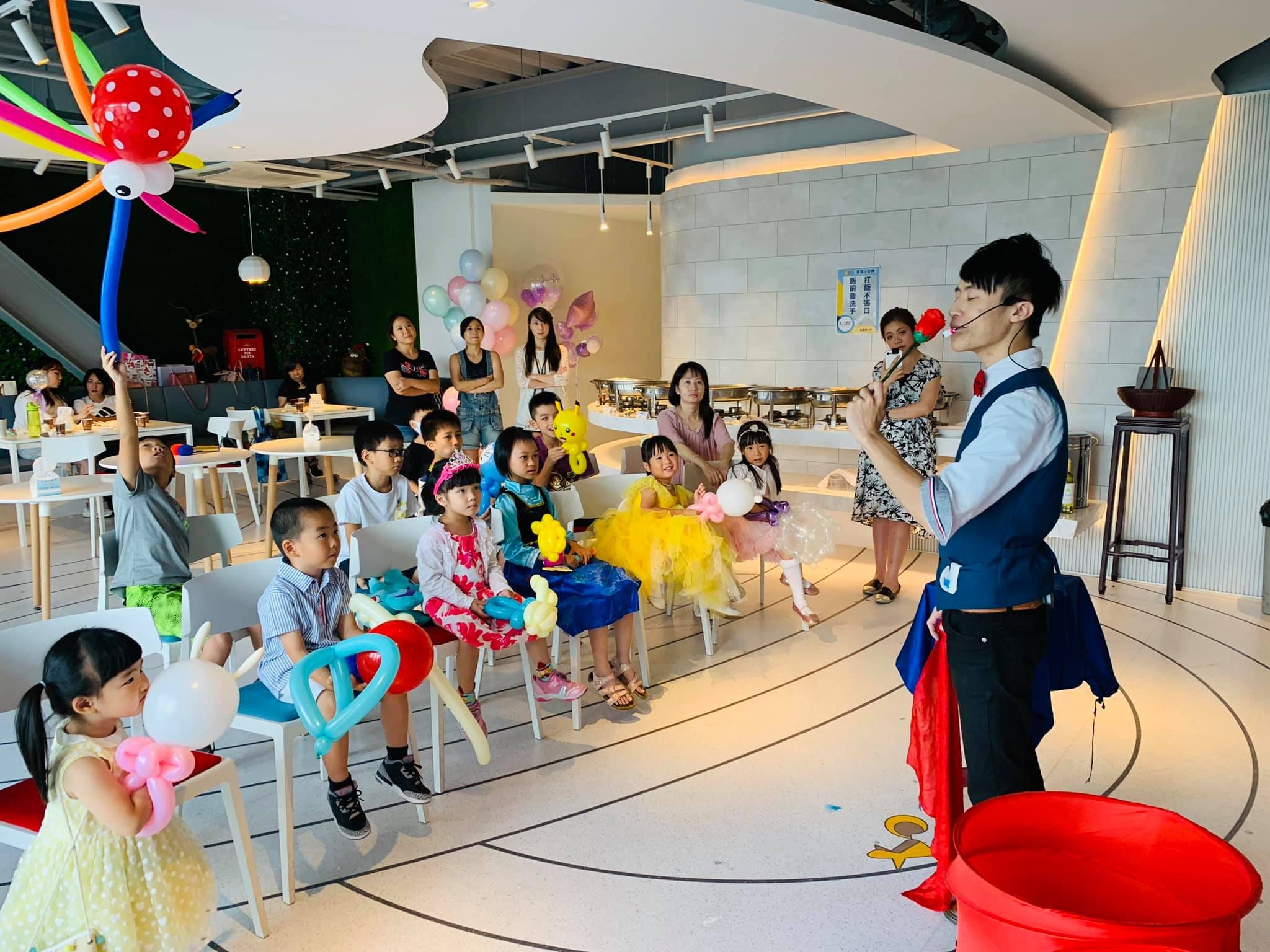 生日派對魔術表演，魔術師口咬紅玫瑰，公主裝小朋友坐著看