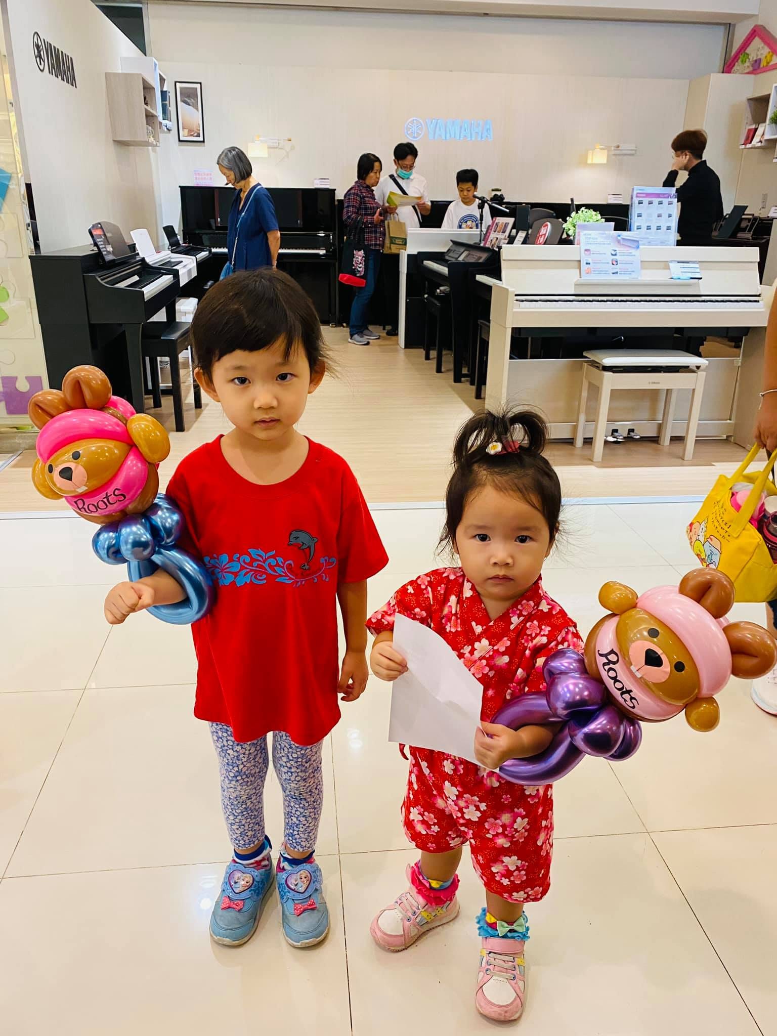 兩個小女孩在板橋大遠百樓層裡拿著粉紅色海狸氣球手環