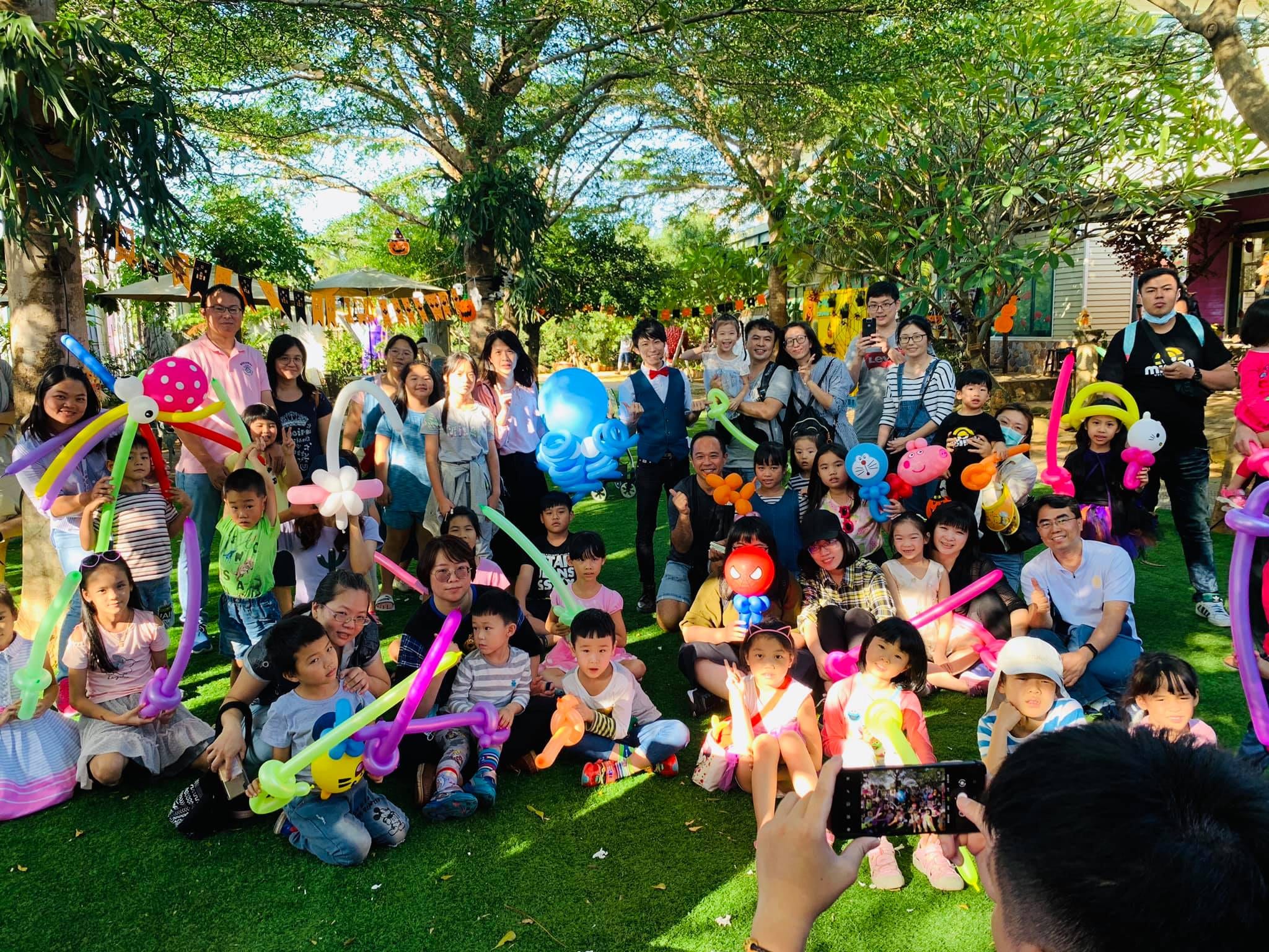 一小時魔術表演後，大人小孩拿著造型氣球在草地上大合照